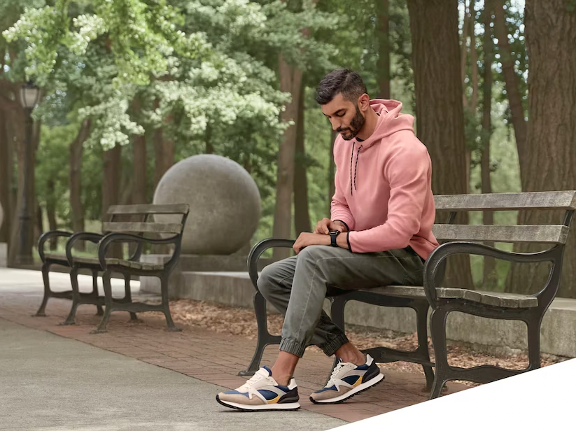 A man sitting on a park bench looking at his Garmin Venu 3