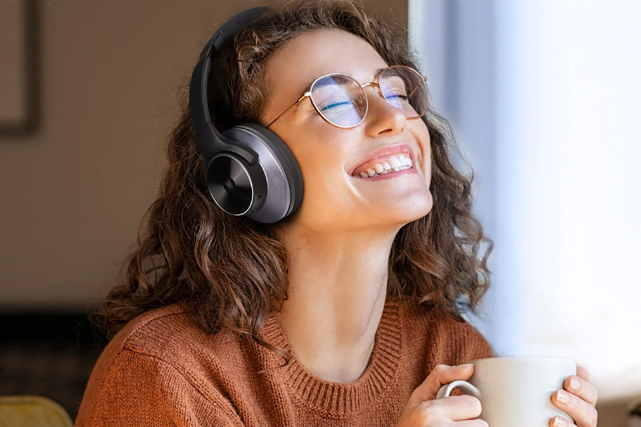 Una mujer con cabello castaño y gafas escucha con auriculares negros.