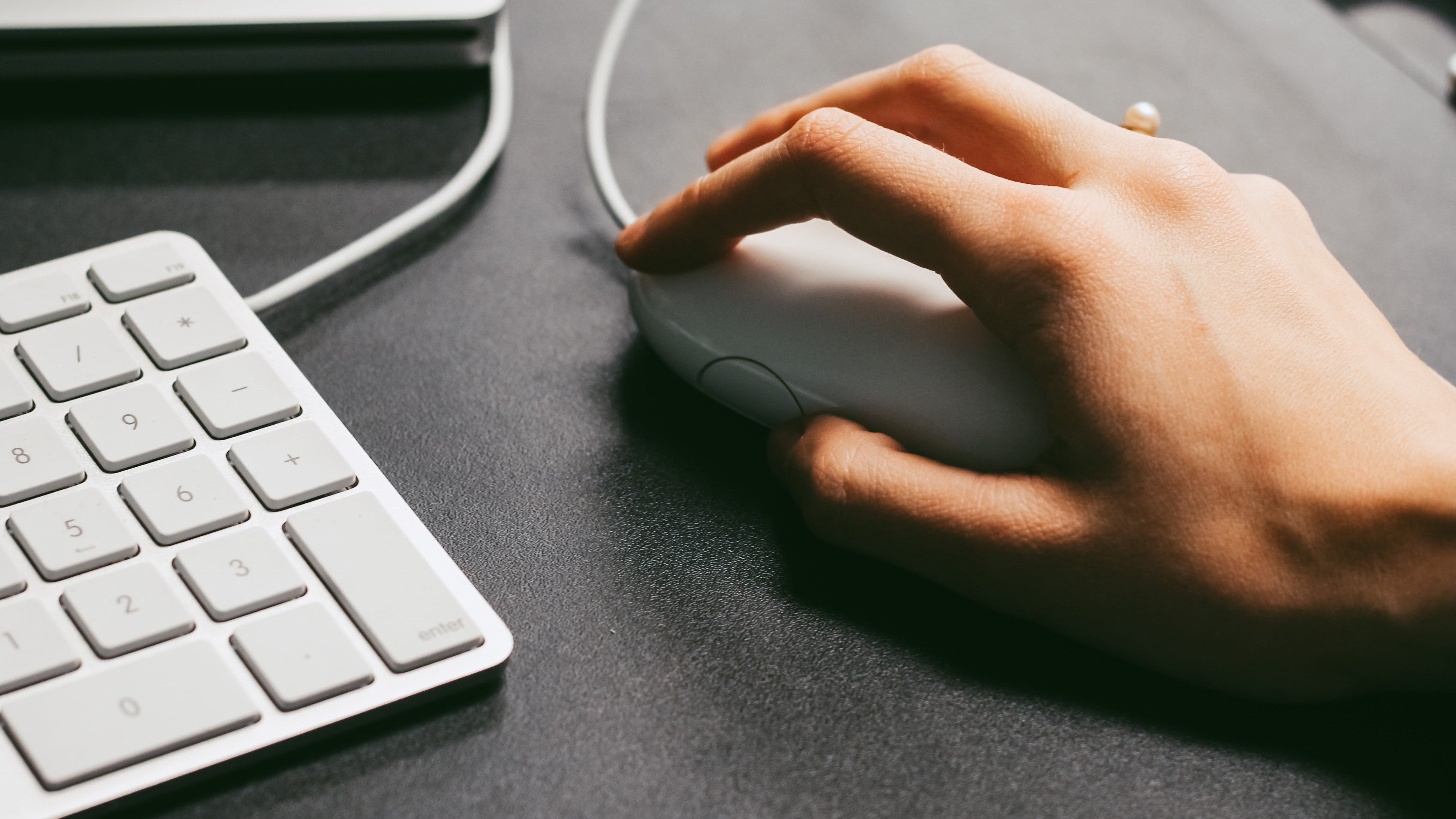 Hand on a mouse next to a keyboard