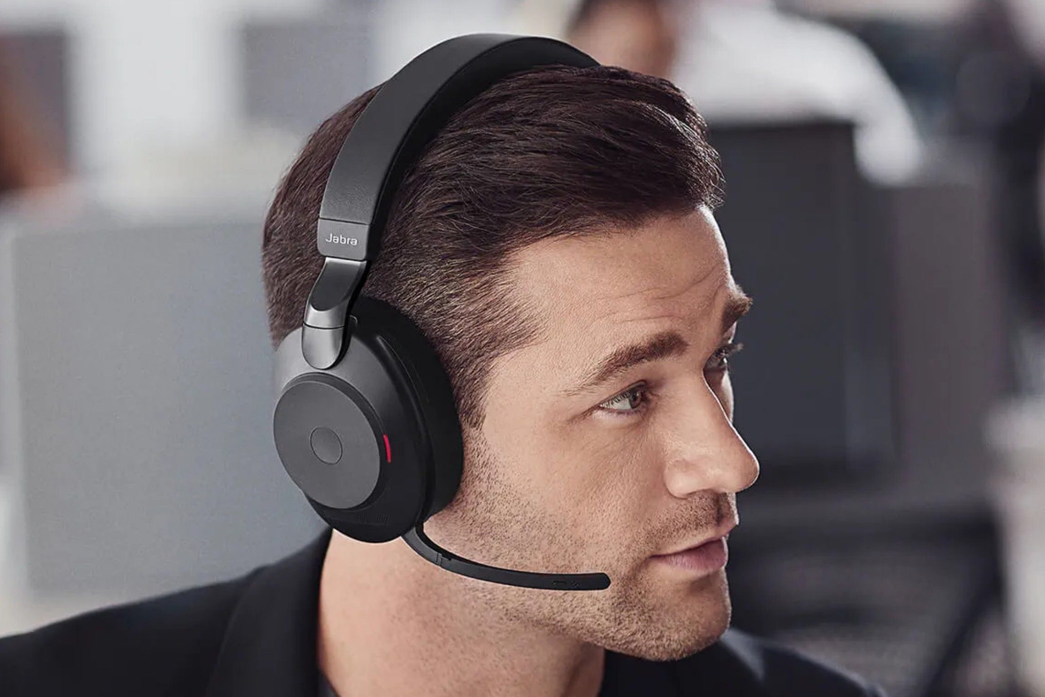 A man with a Jabra Evolve 2 85 headset on and the boom mic unfolded closed to his mouth.