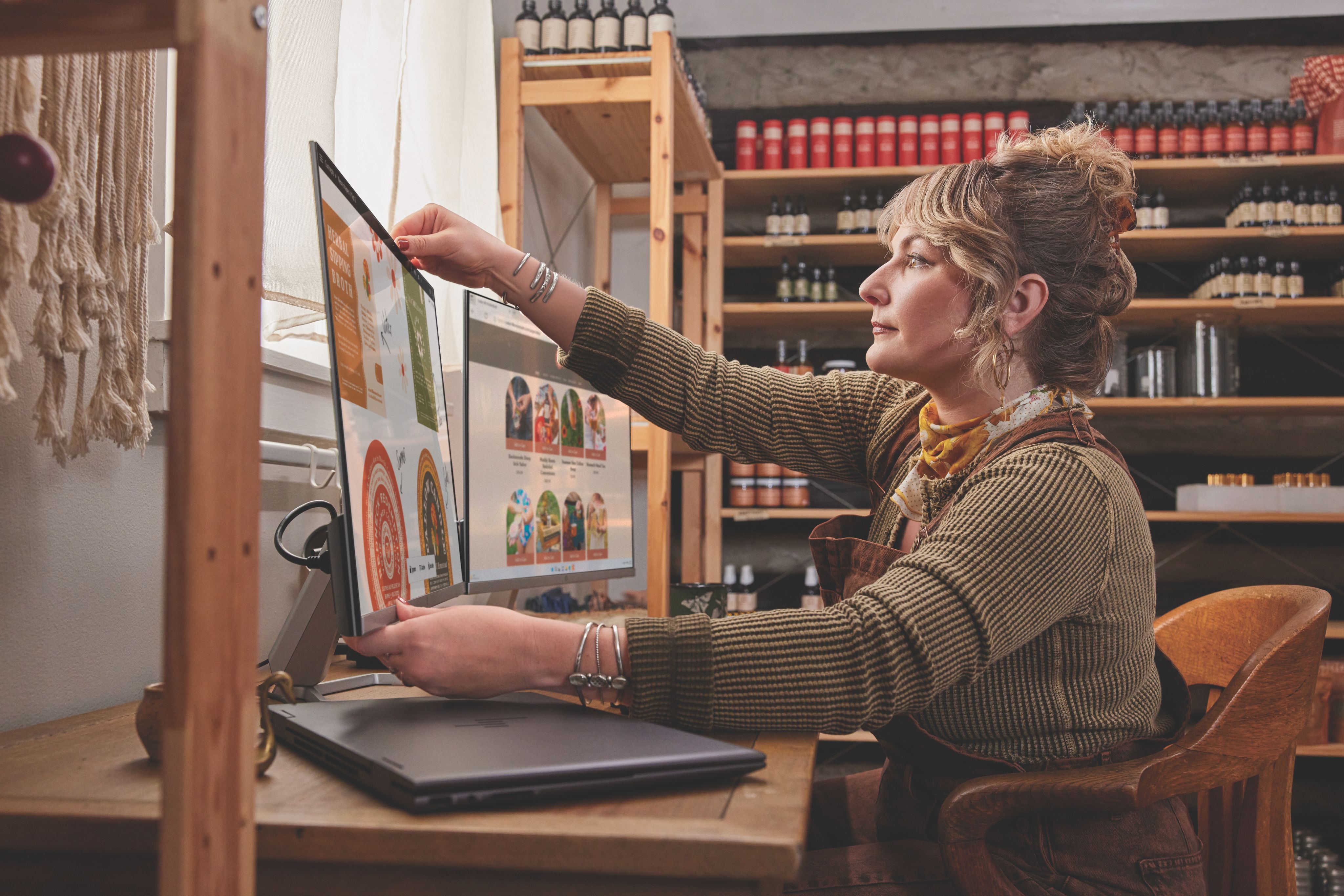 Mujer ajustando la posición de un monitor en un escritorio