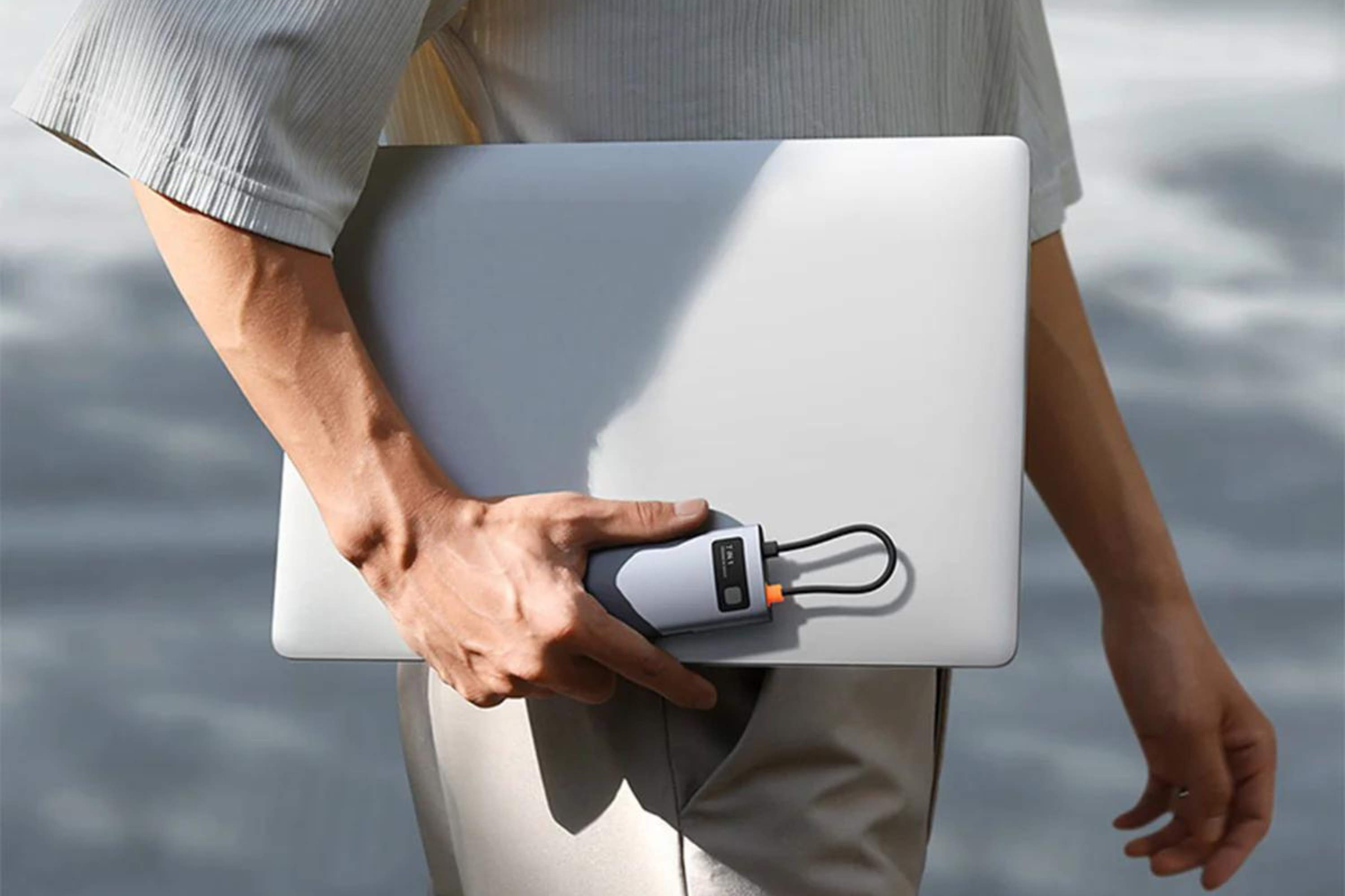 Baseus 7-in-1 USB hub in hand of a person holding laptop 