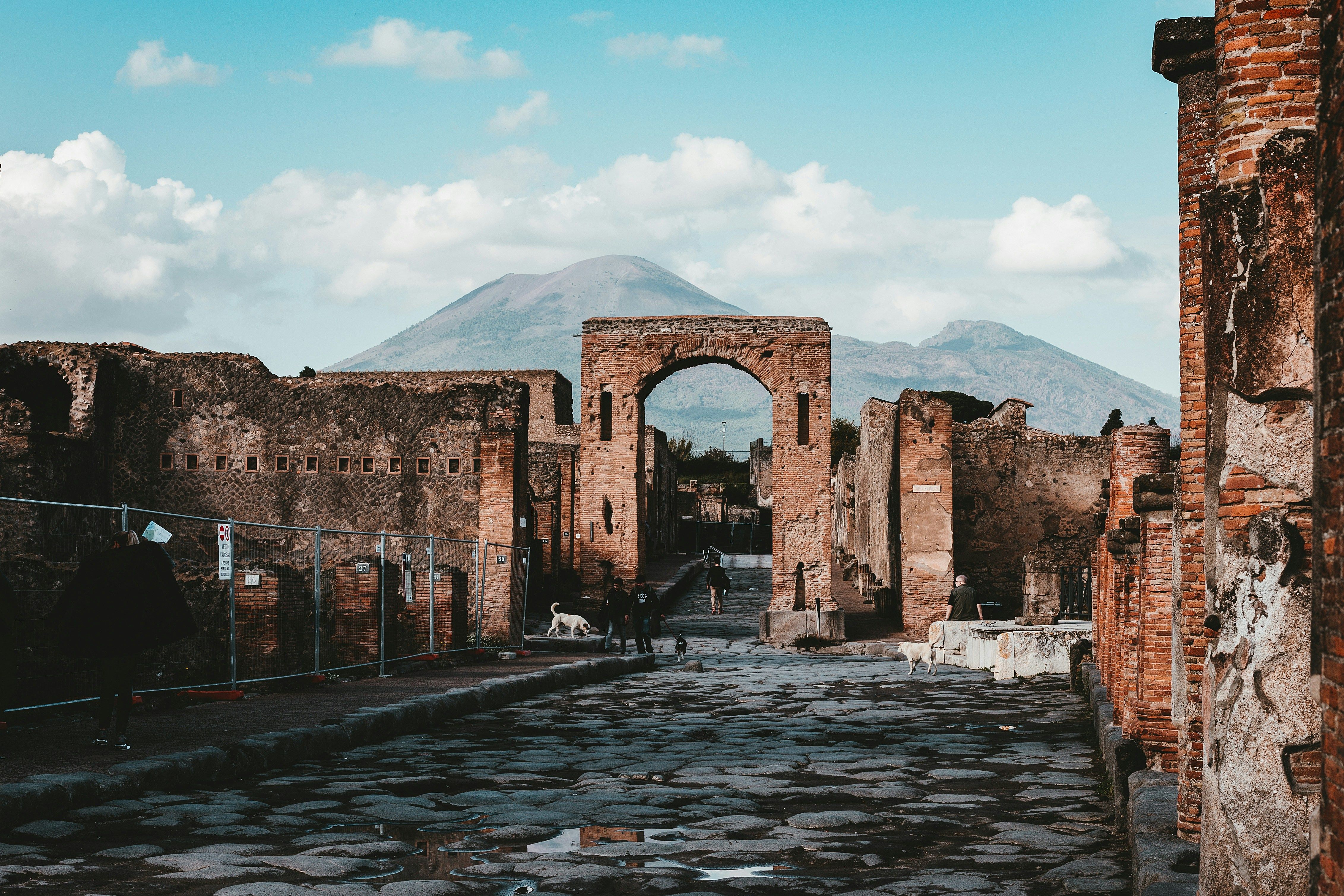 Pompeii arch at a cobble road with people walking along