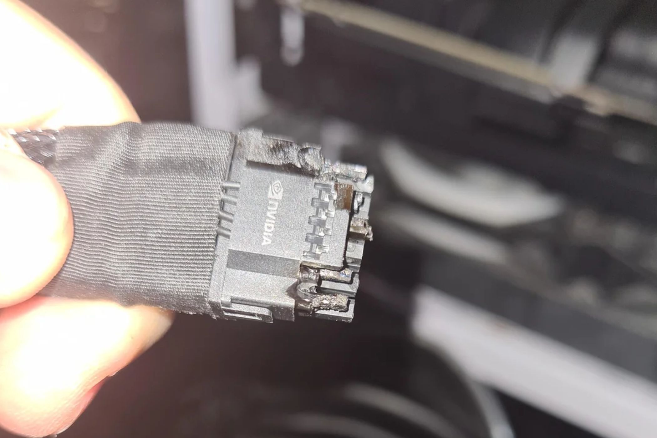 An image showing a person holding a burnt 12VHPWR connector in their hand.