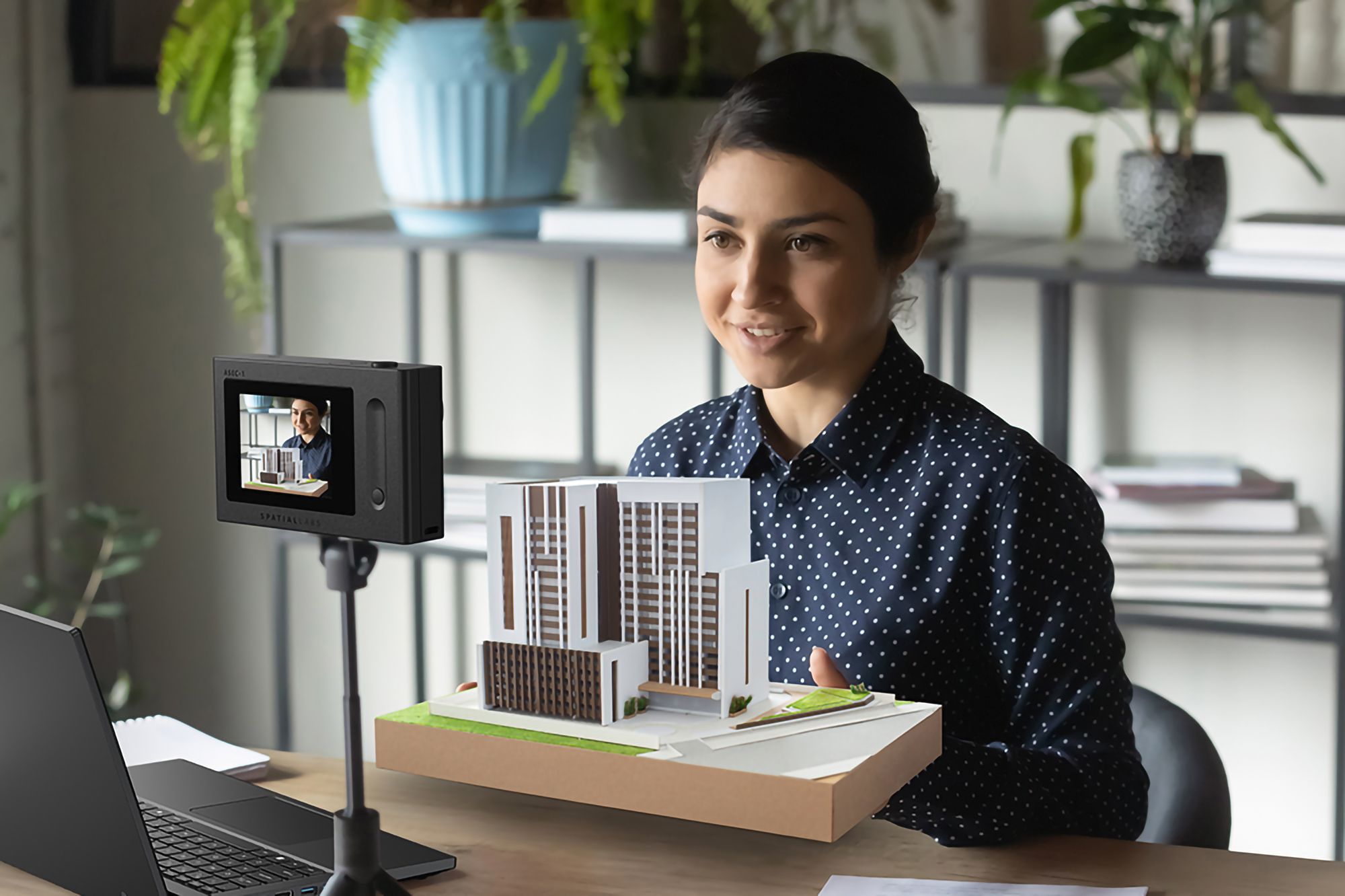 Mujer sentada frente a una cámara estéreo Acer SpatialLabs Eyes con un modelo 3D en la mano