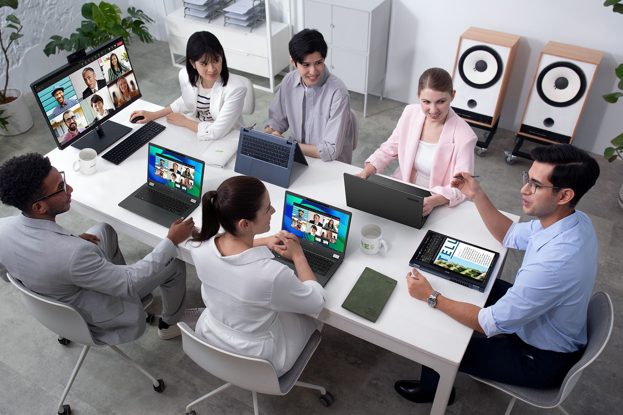 Un grupo de personas se sienta en una sala de reuniones con varias computadoras portátiles en el escritorio.