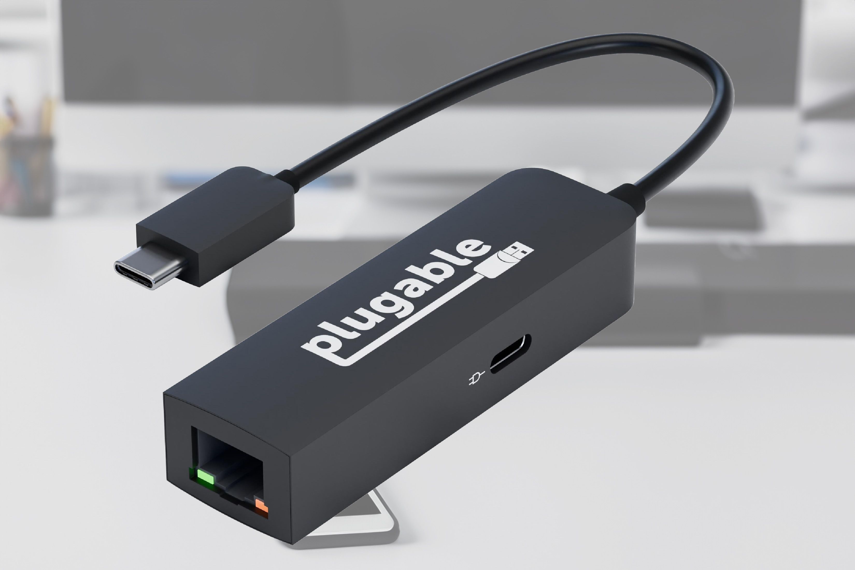 USB-E2500PD enchufable con un fondo de un escritorio de oficina con una computadora encima