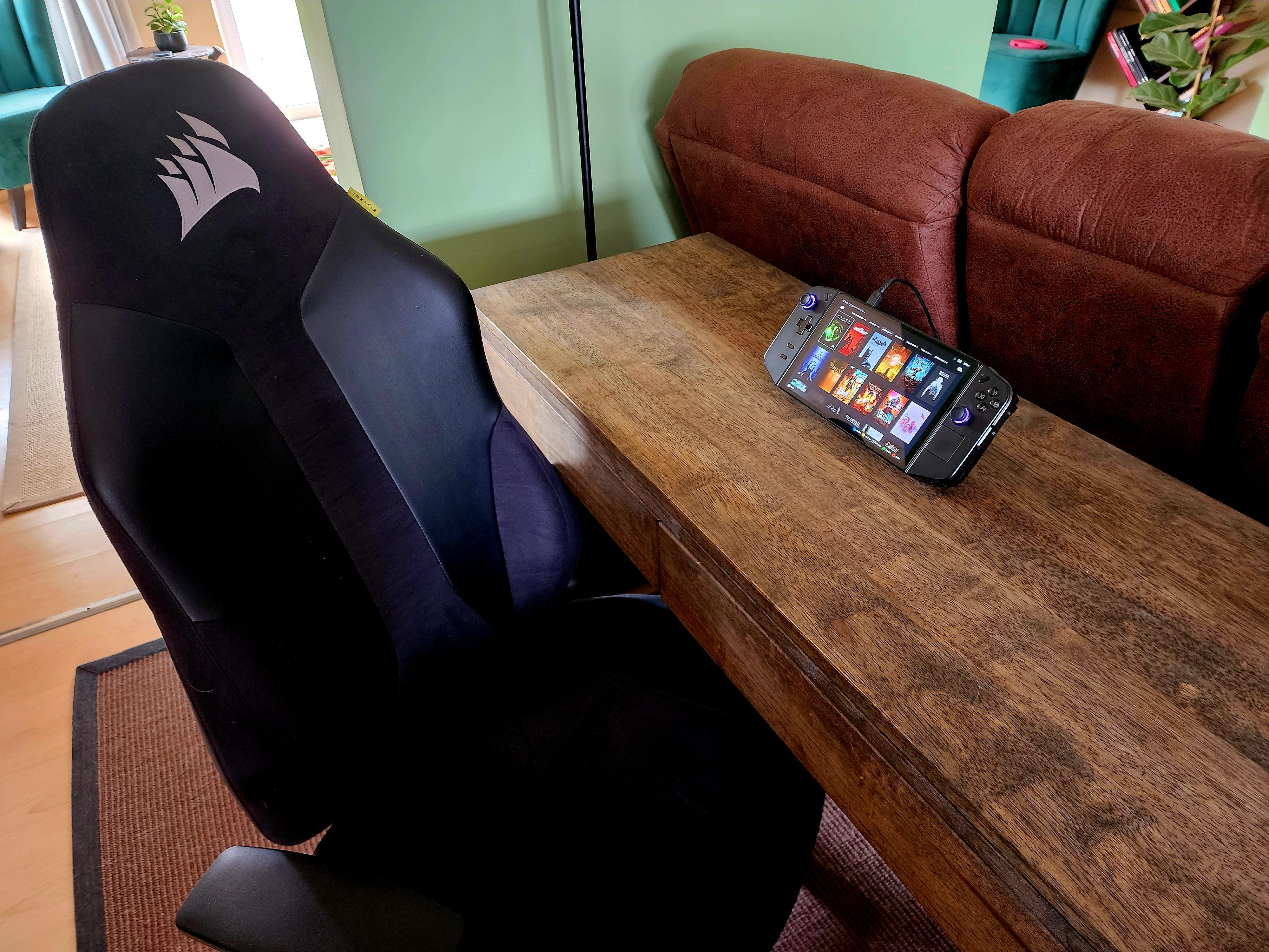 A Lenovo Legion Go on a desk next to a gaming chair.