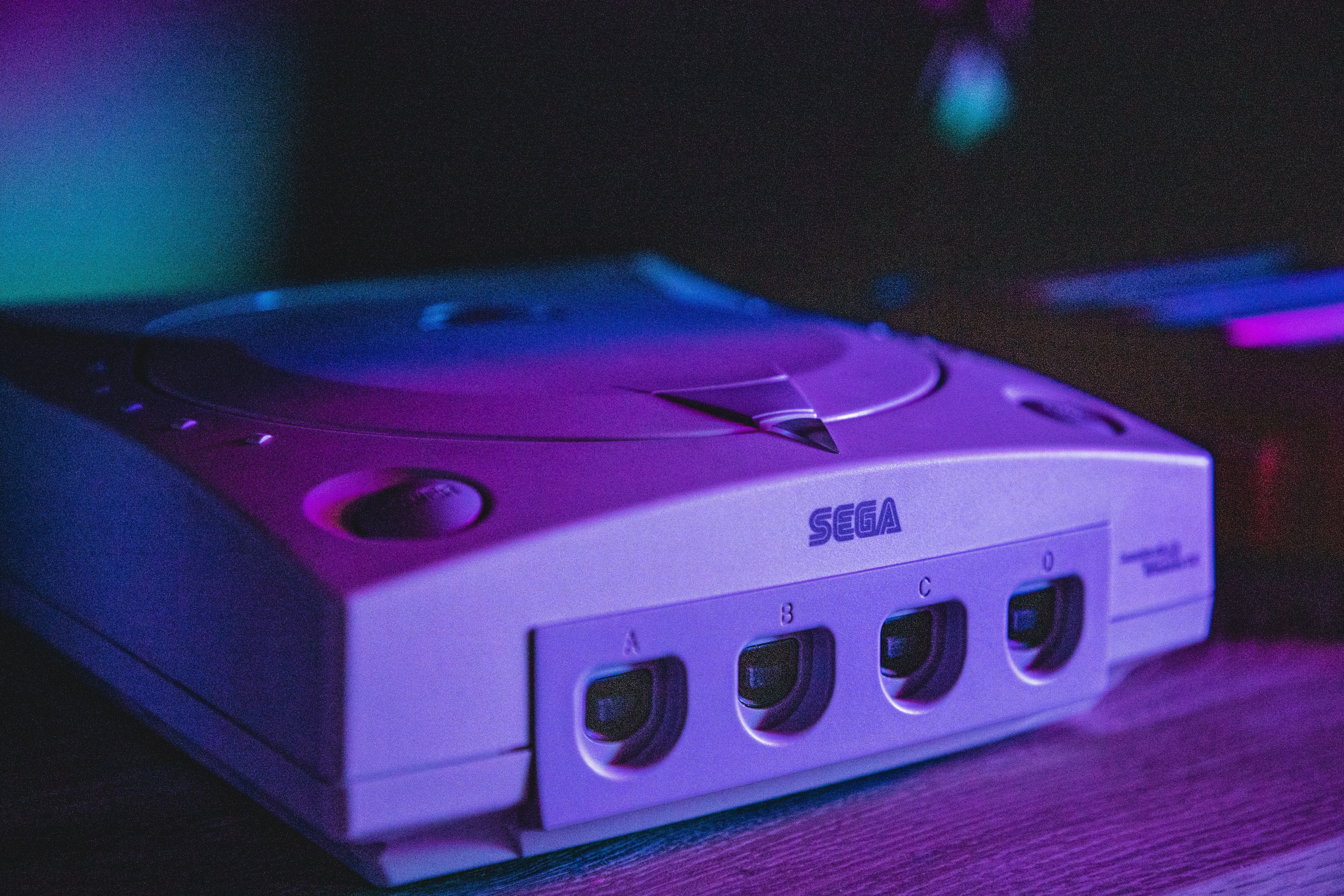 Una Sega Dreamcast con una iluminación violeta tenue.