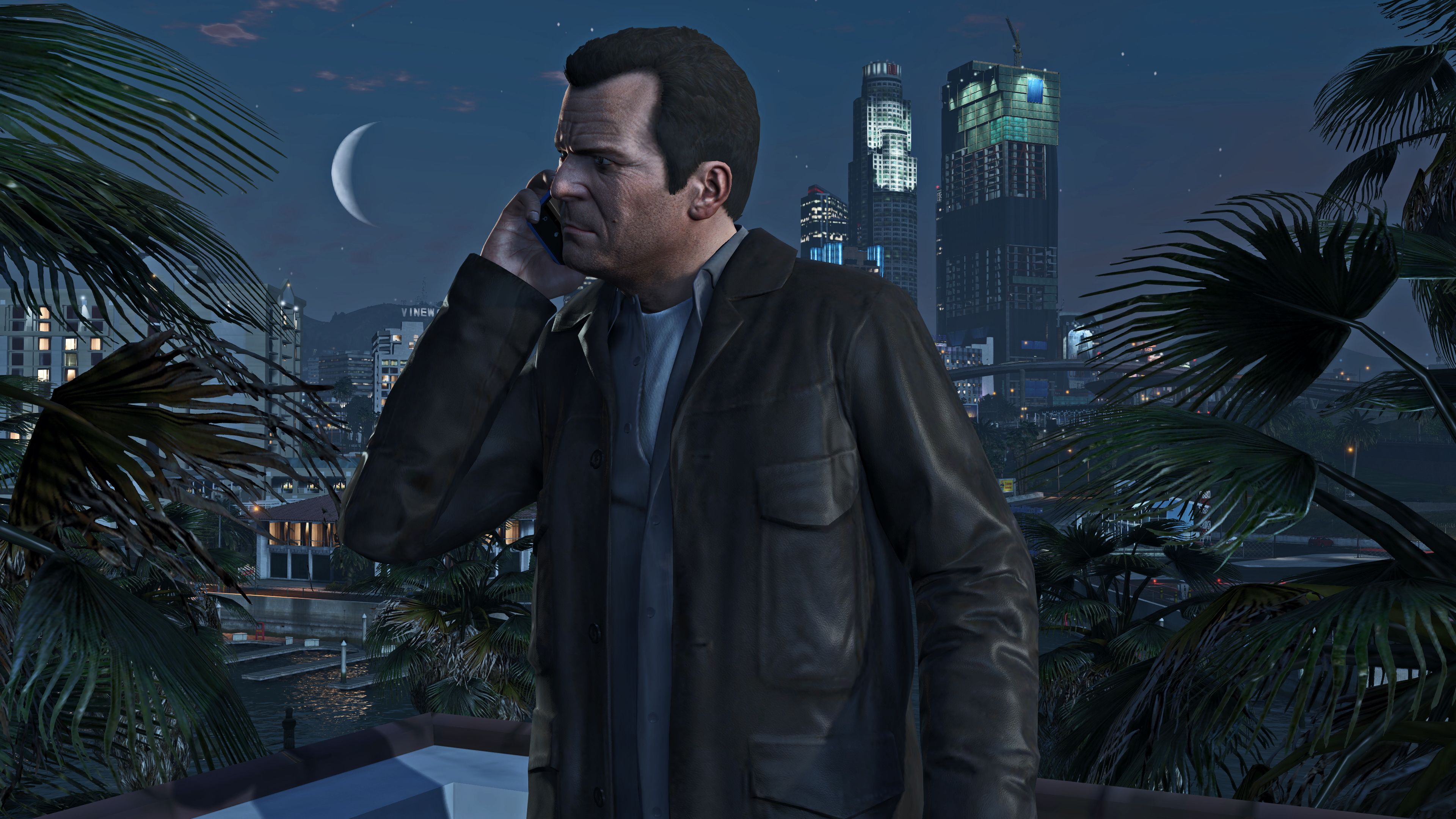 Скриншот от Grand Theft Auto V of Man, разговаривающего по телефону ночью с городским горизонтом позади него