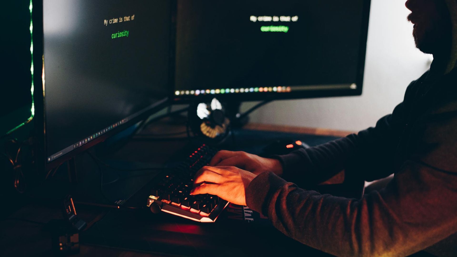 Hacker escribiendo en un teclado sentado en la oscuridad