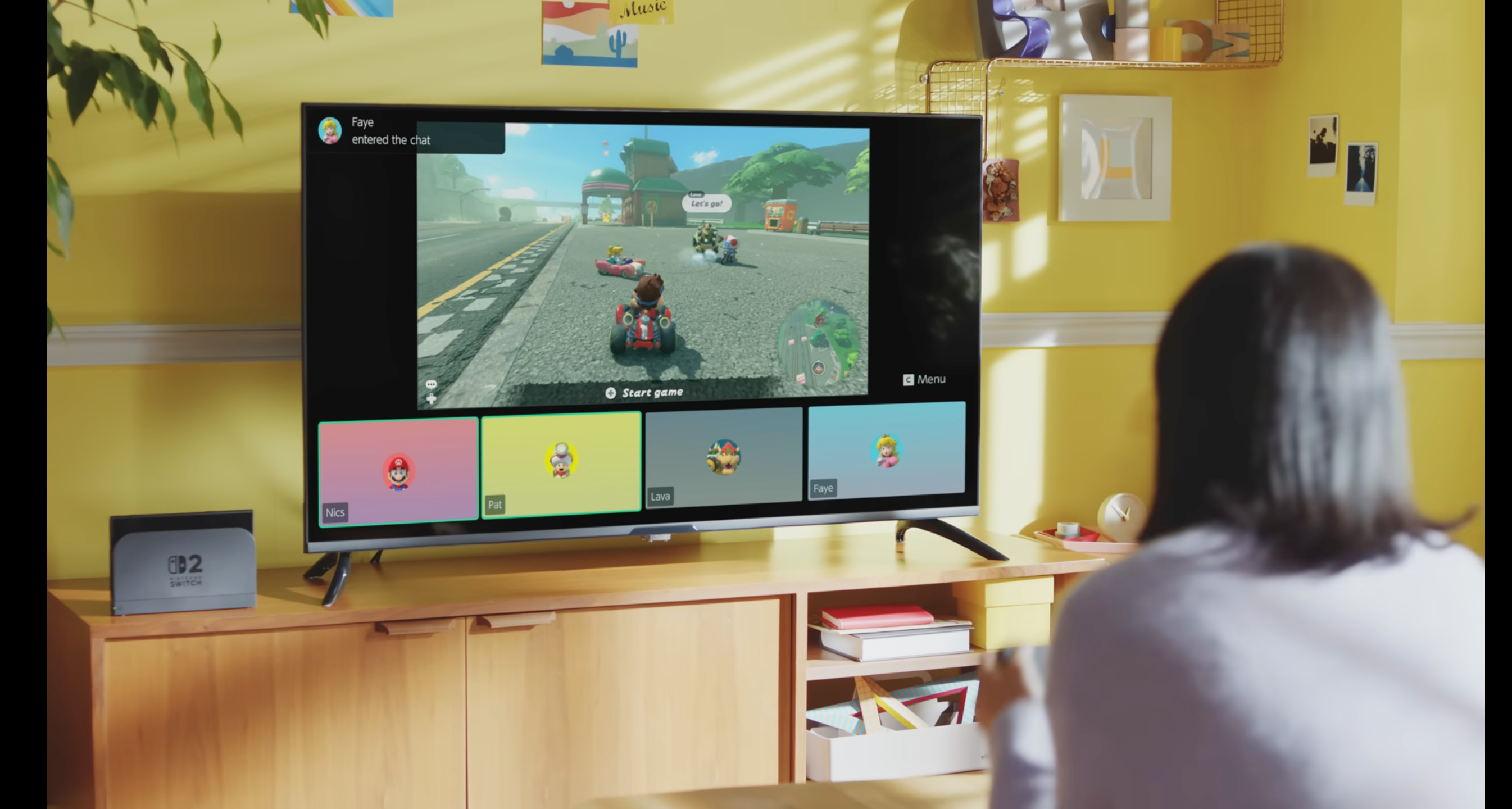 Womman, сидящий, глядя на телевизор, показывающий игру Nintendo Switch 2 с интерфейсом GameChat