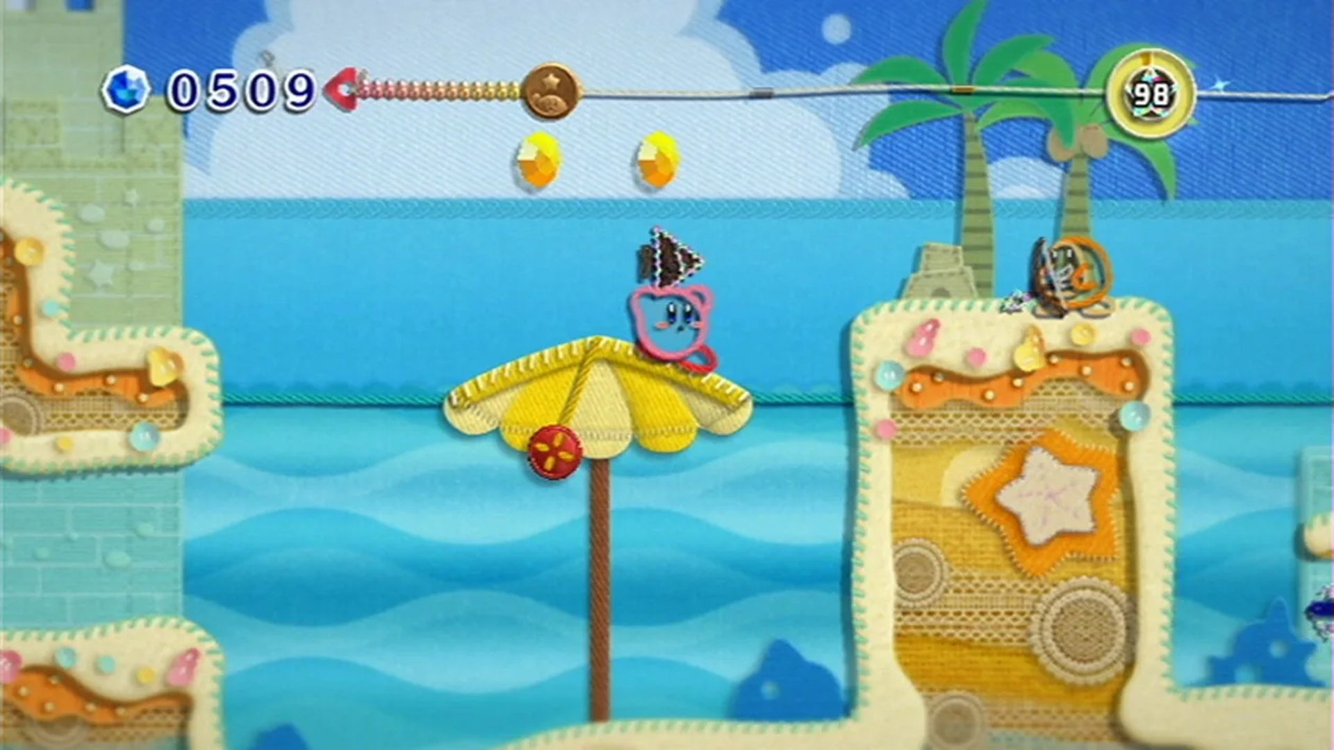 A screenshot of Kirby on a beach during gameplay from Kirby's Epic Yarn