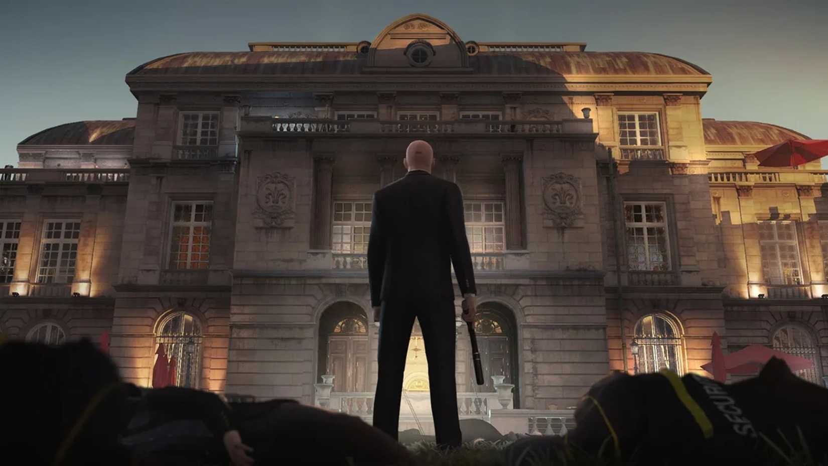 A screenshot of Agent 47 standing outside of a building in Hitman
