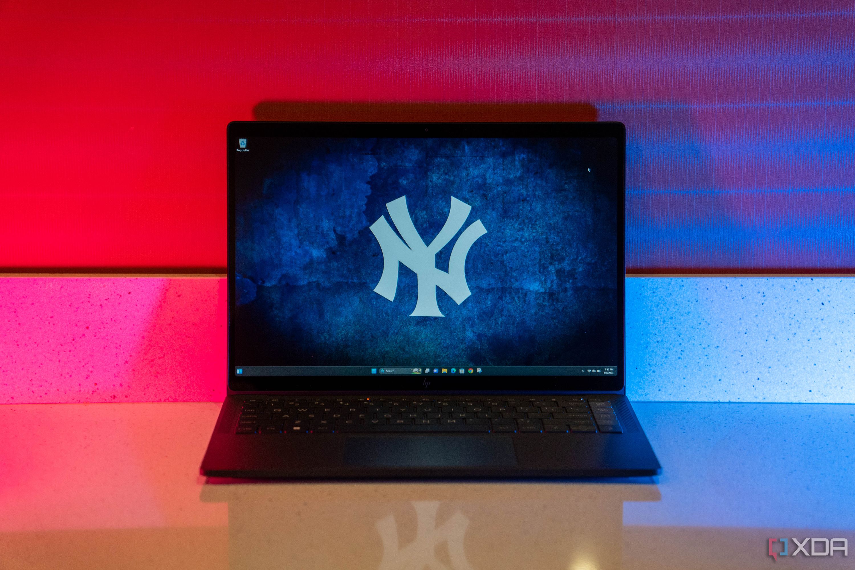 Black laptop with Yankee logo wallpaper, with blue and magenta lighting.