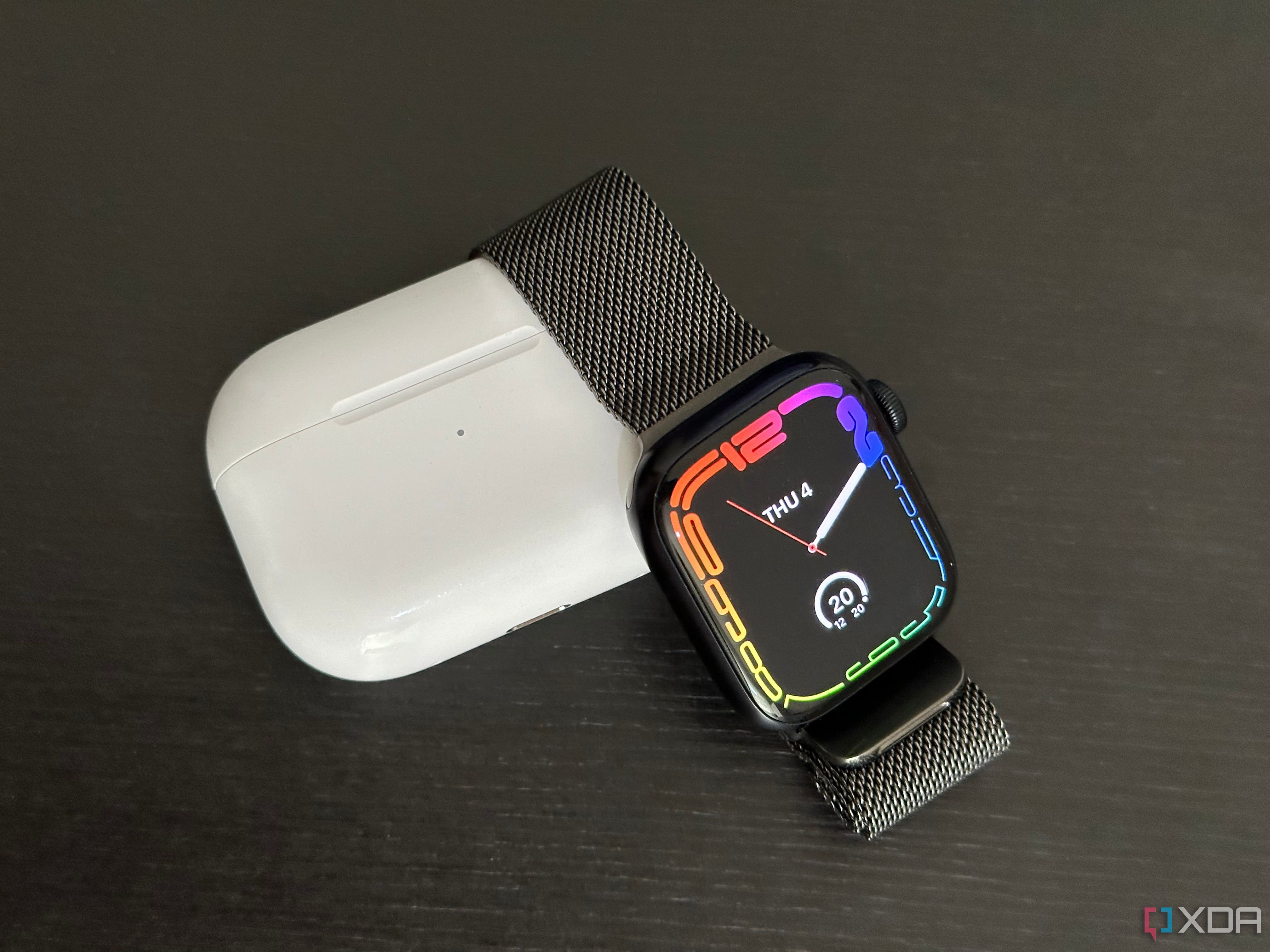 Midnight Apple Watch Series 7 with Graphite Milanese Loop next to AirPods Pro 2