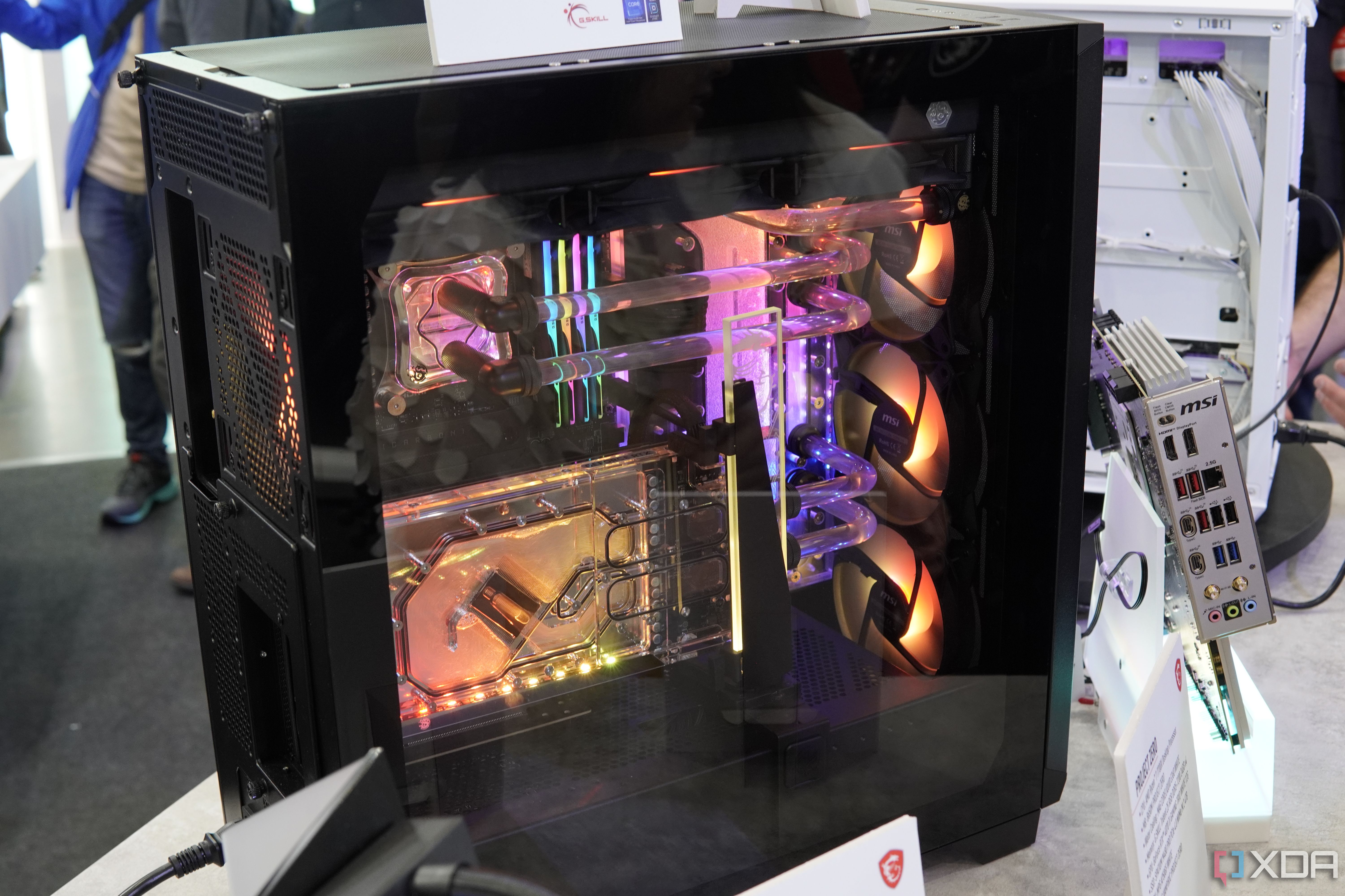 Vista lateral en ángulo de la PC MSI Project Zero que muestra tubos de refrigeración por agua, bloques de agua translúcidos e iluminación RGB en varios colores