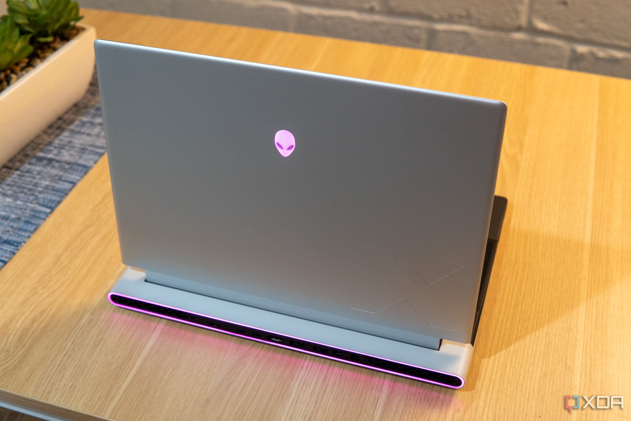 Rear angled view of the Alienware x16 on a wooden desk