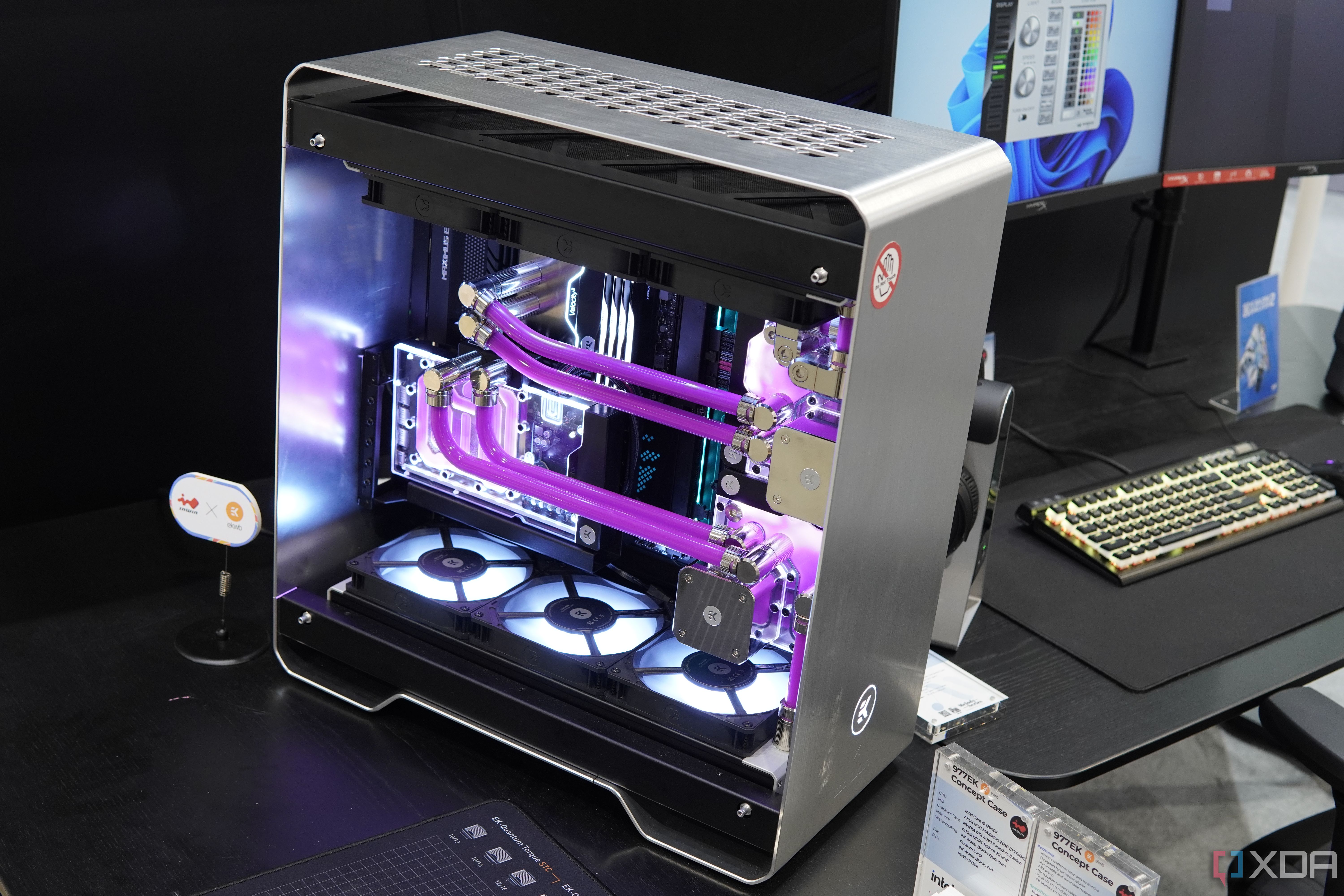 Angled view of the custom InWin 977EK PC build featuring a silver-colored metal chassis and two liquid cooling loops with pink liquid