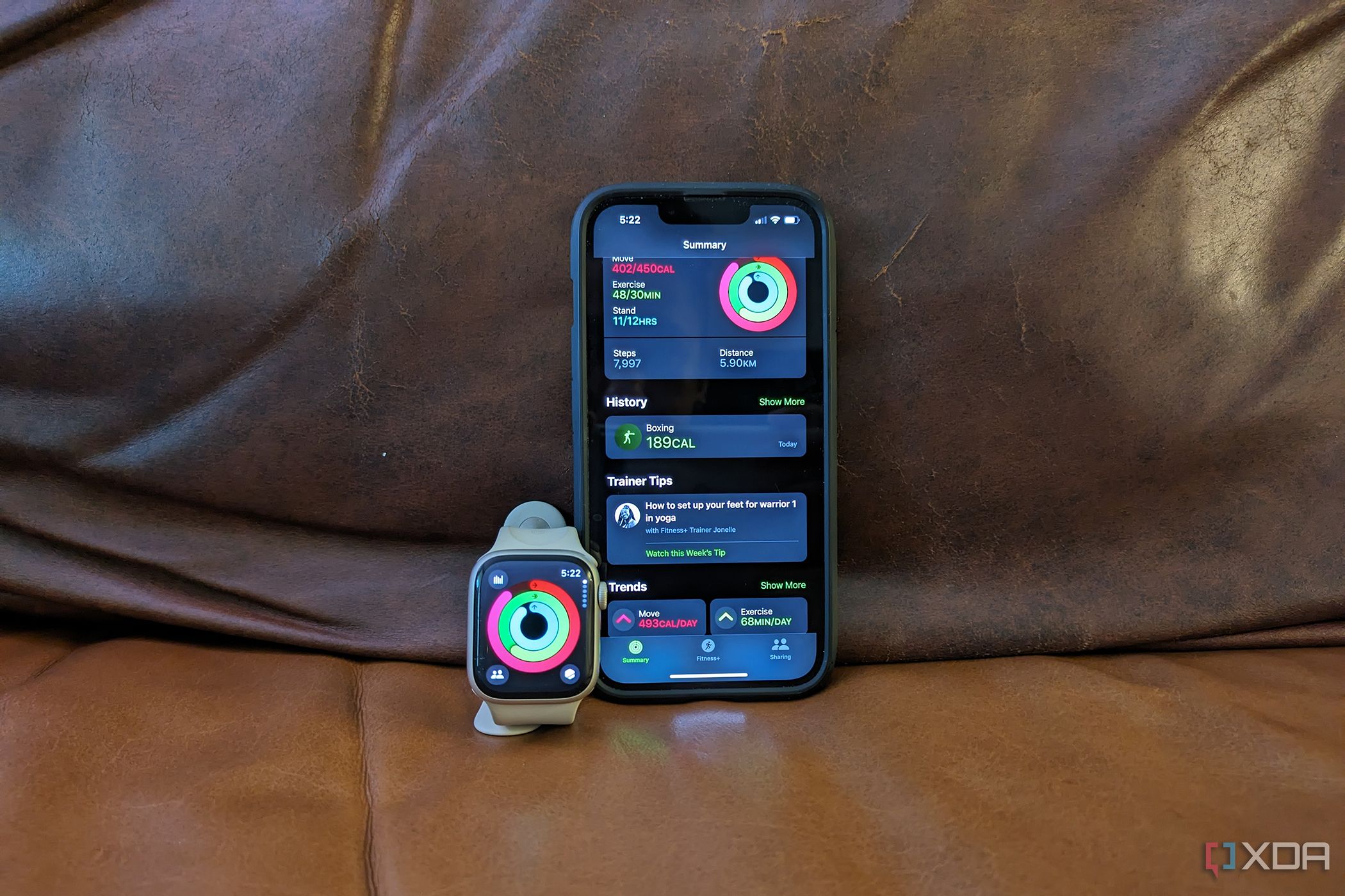 The Apple Fitness app on an iPhone 14 and Apple Watch propped up side by side.