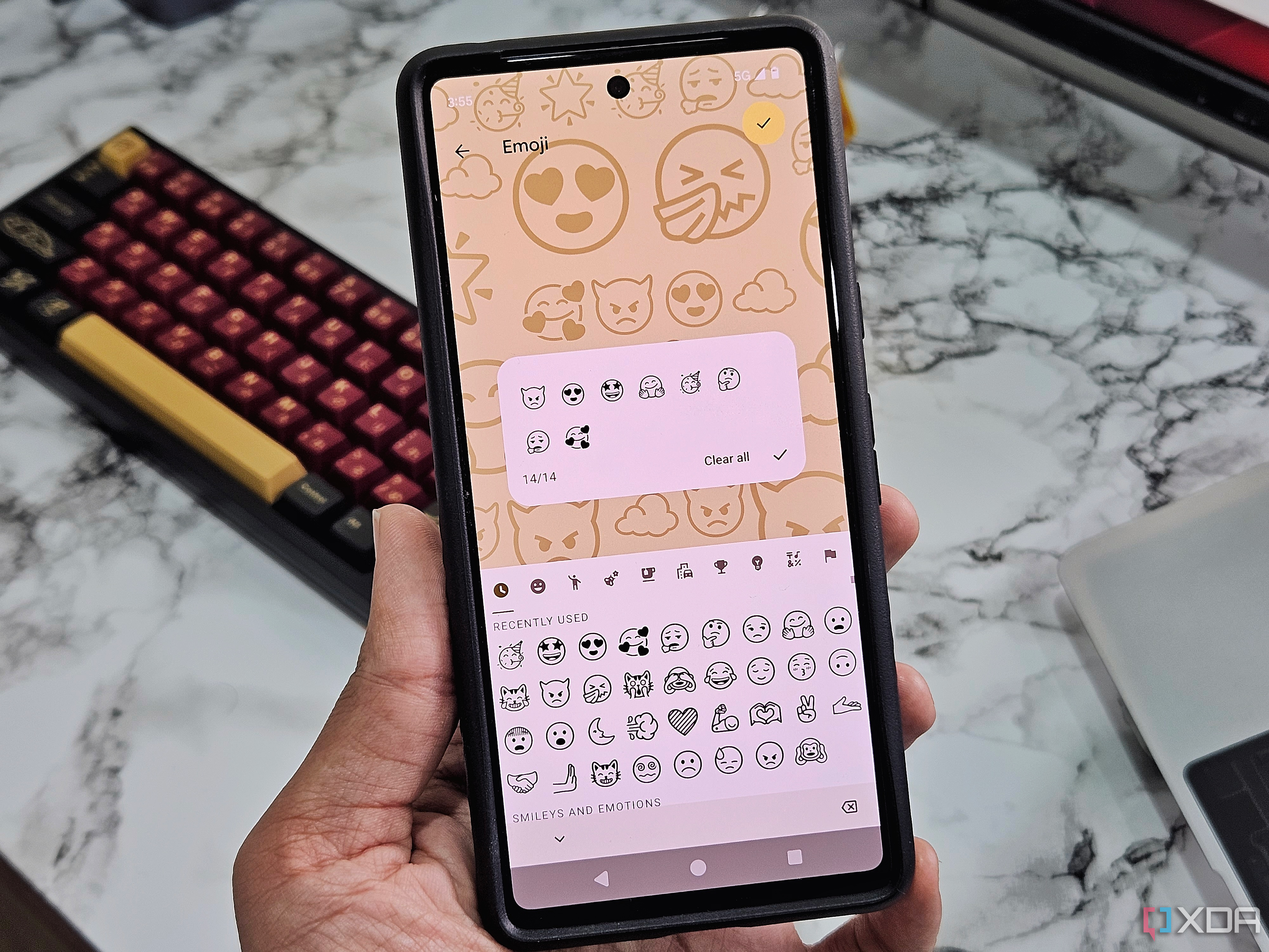 An image showing a person holding a Pixel 7 that's displaying the Emoji workshop.