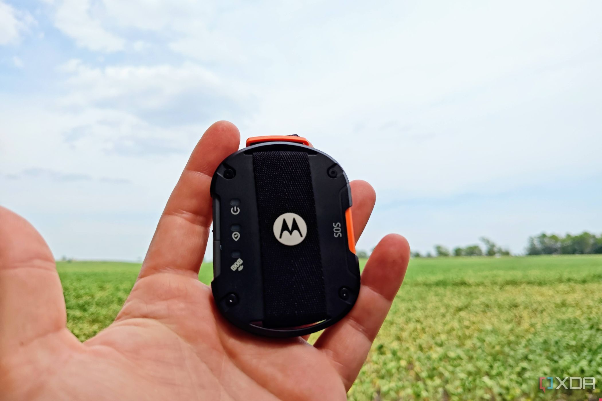 Motorola Defy Satellite Link in hand with open field and sky behind it