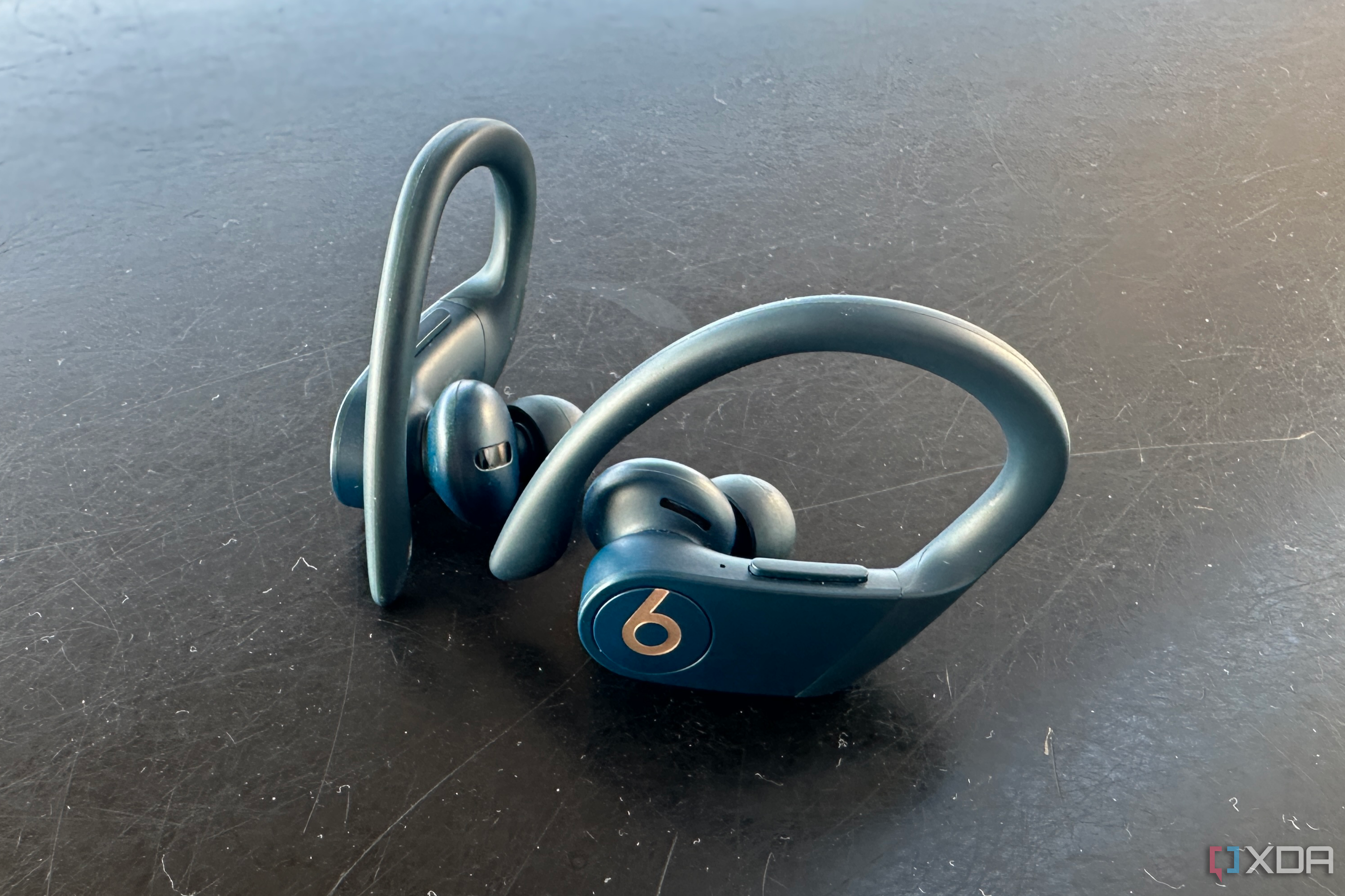 Two Powerbeats Pro earbuds resting on a table.