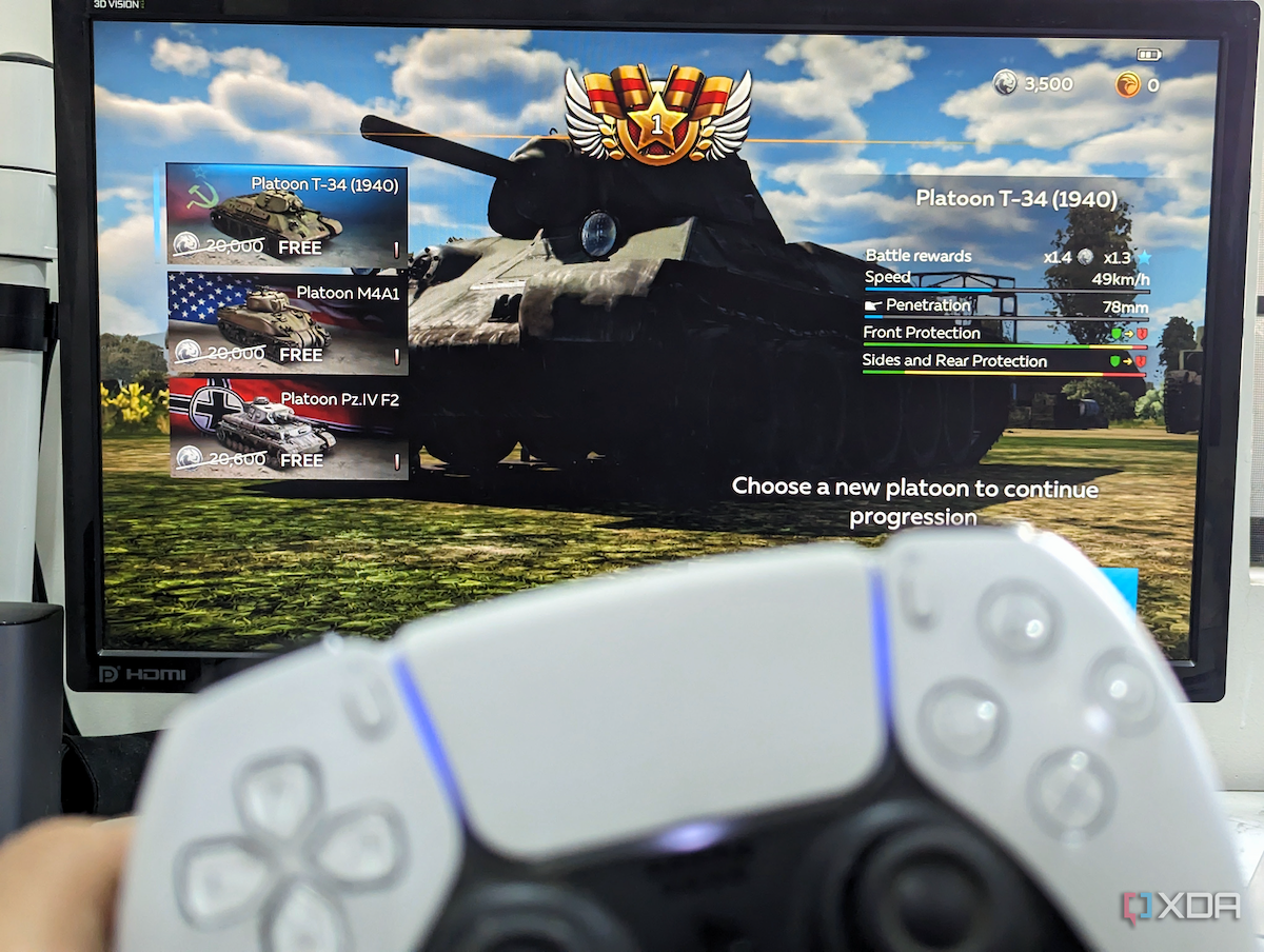 An image showing a PS5 DualSense controller with a monitor in the background running War Thunder Mobile game on DeX.