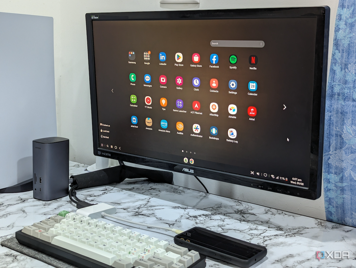 An image showing a Samsung DeX setup which includes a monitor, an HDMI multiport adapter, a keyboard, and the phone.