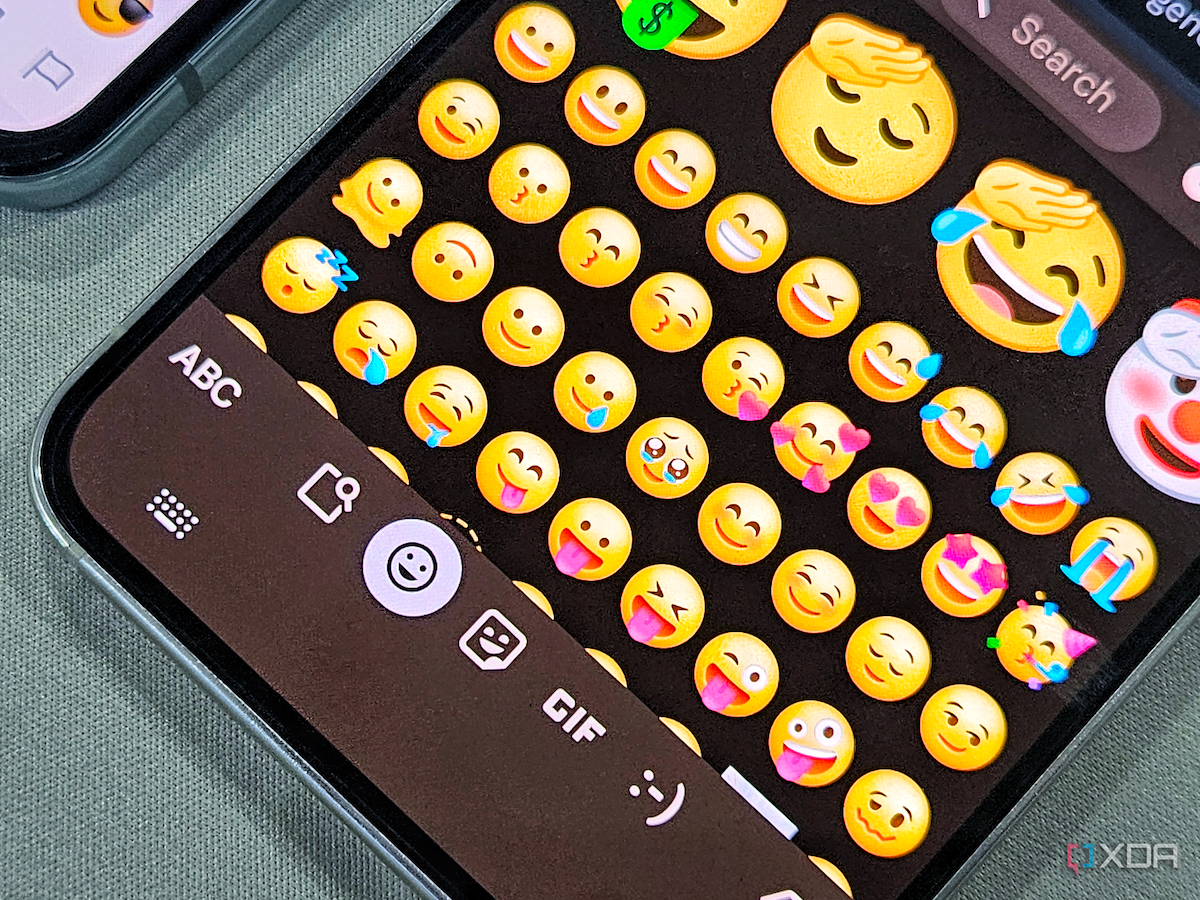 An image showing a Galaxy S23 kept on a desk displaying emojis in One UI 6.