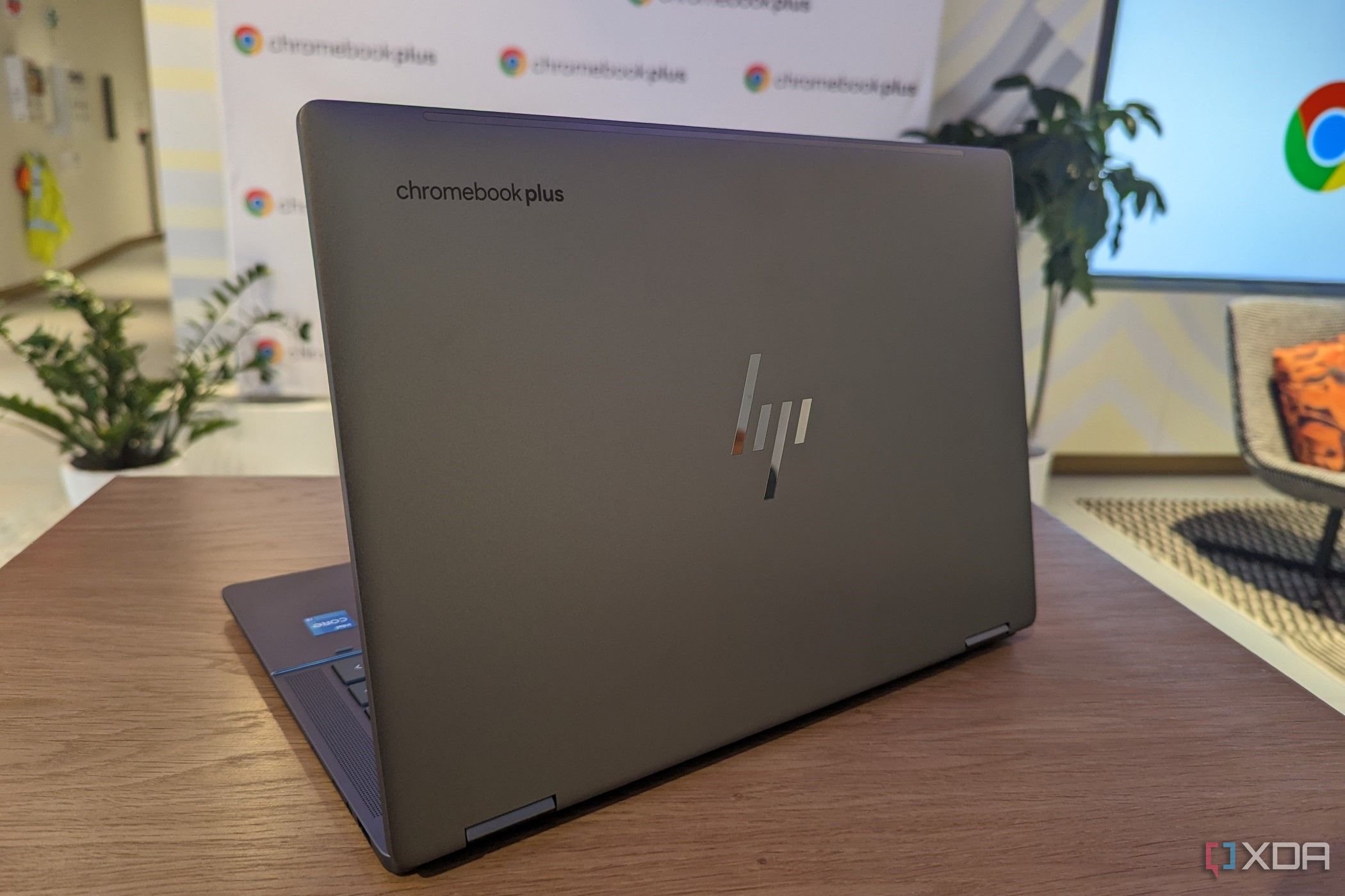 An HP Chromebooks Plus model sitting on a table with GOogle Chrome logo in the back