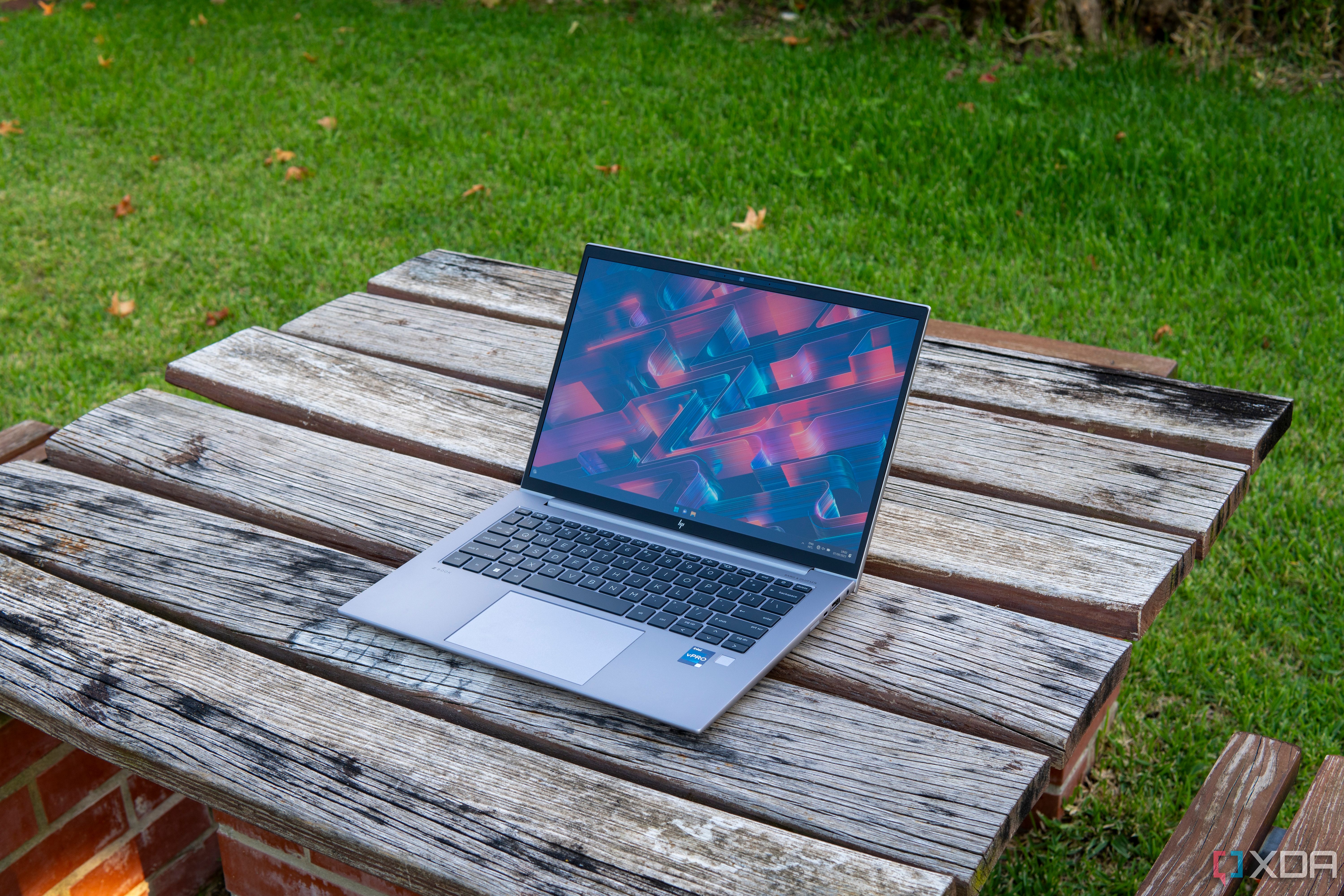 HP ZBook Firefly 14 G10 laptop on a wooden table in a garden.