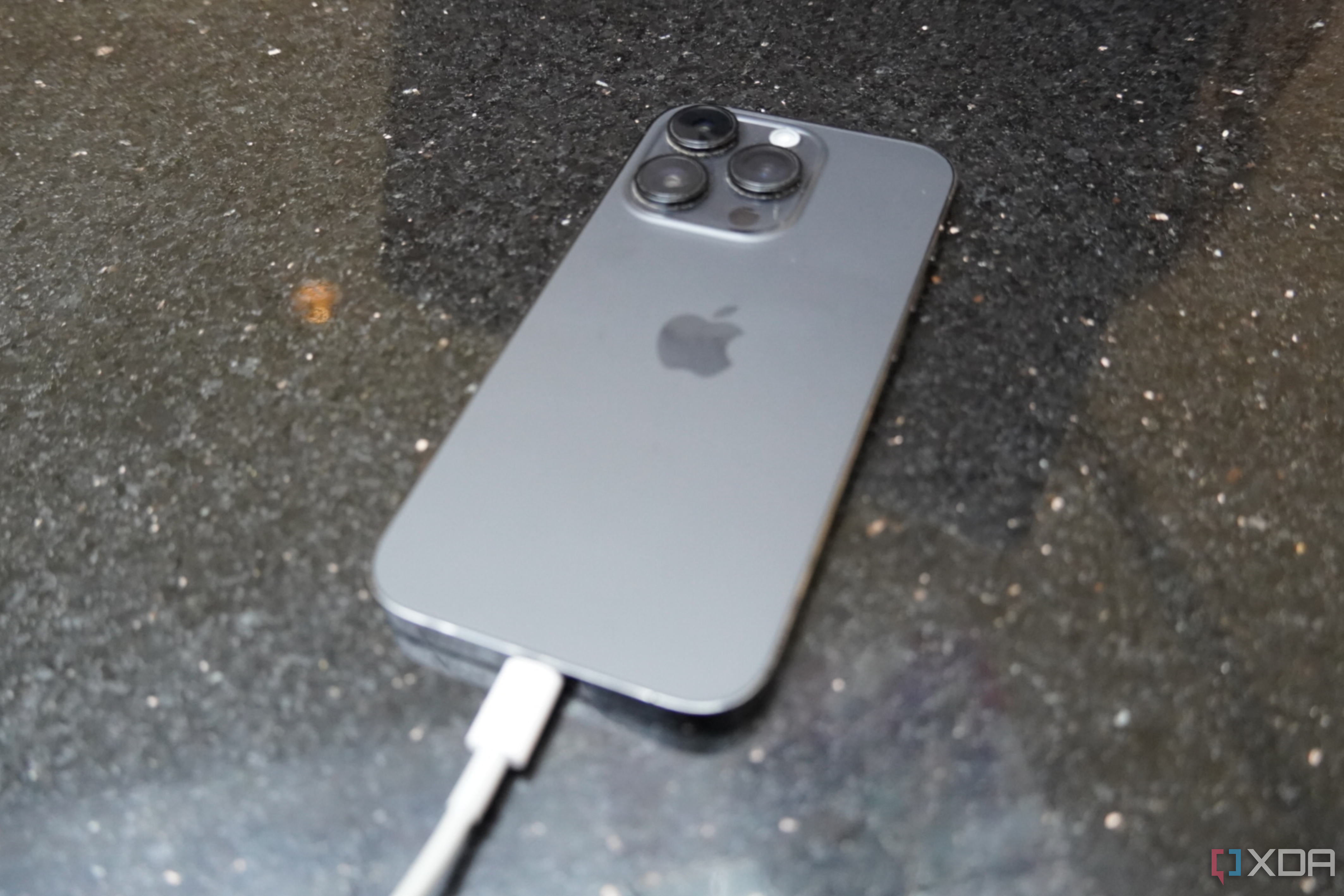 An iPhone 14 Pro connected to a Lightning charger.