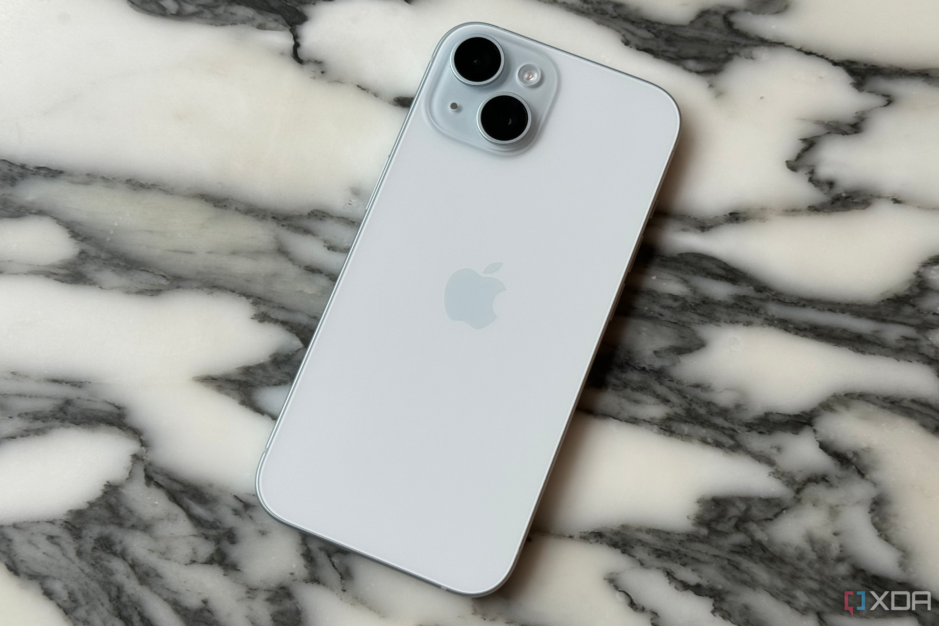 The back of an iPhone 15 on a marble tabletop.