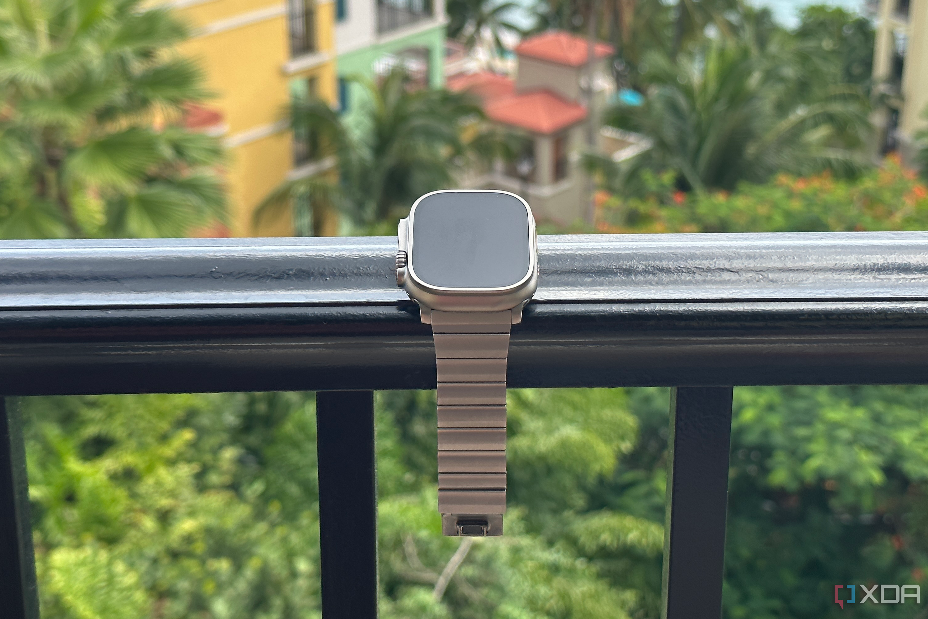 Nomad's Titanium Apple Watch Band on an Apple Watch Ultra sitting on a railing.