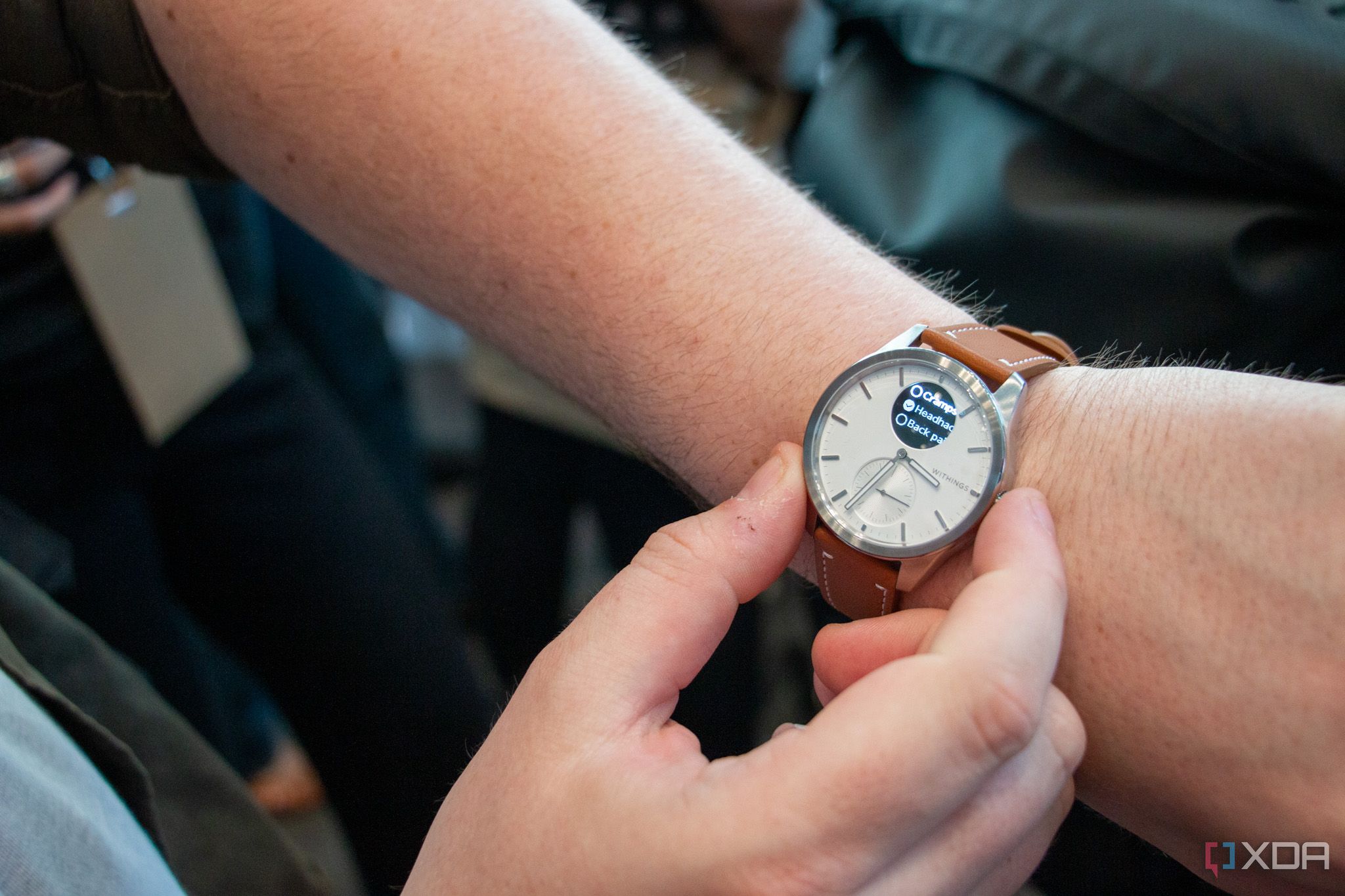 A person wearing a Withings ScanWatch 2 on one wrist while interacting with the watch with their other hand.