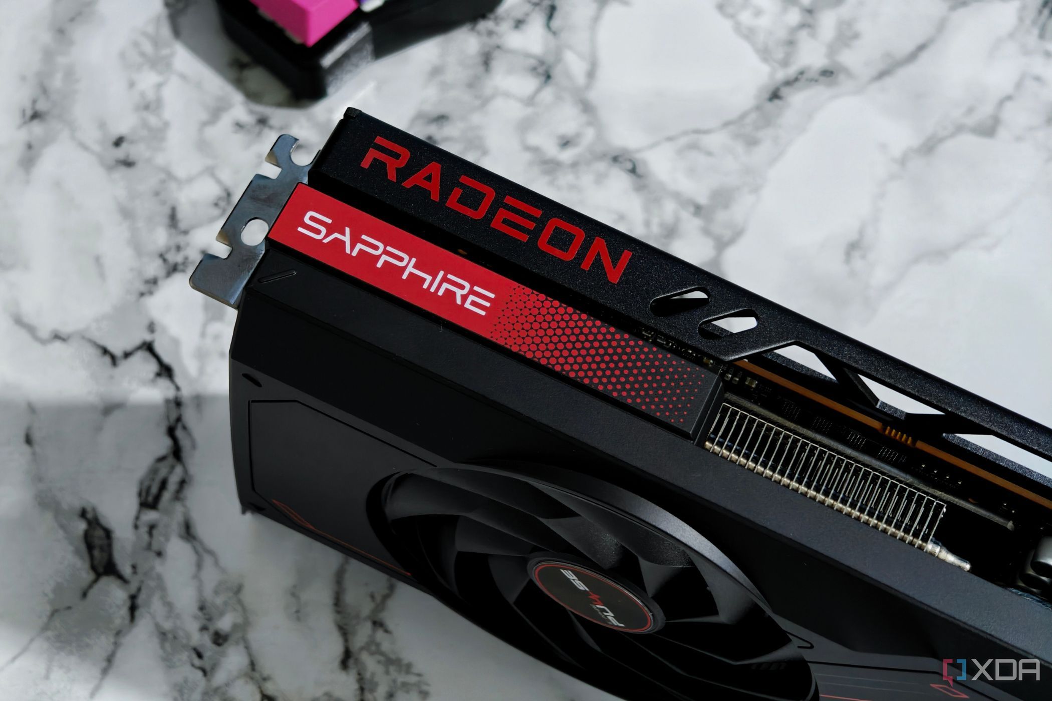 Uma imagem mostrando uma GPU AMD Radeon RX 7700 XT mantida em uma mesa com acabamento em mármore.