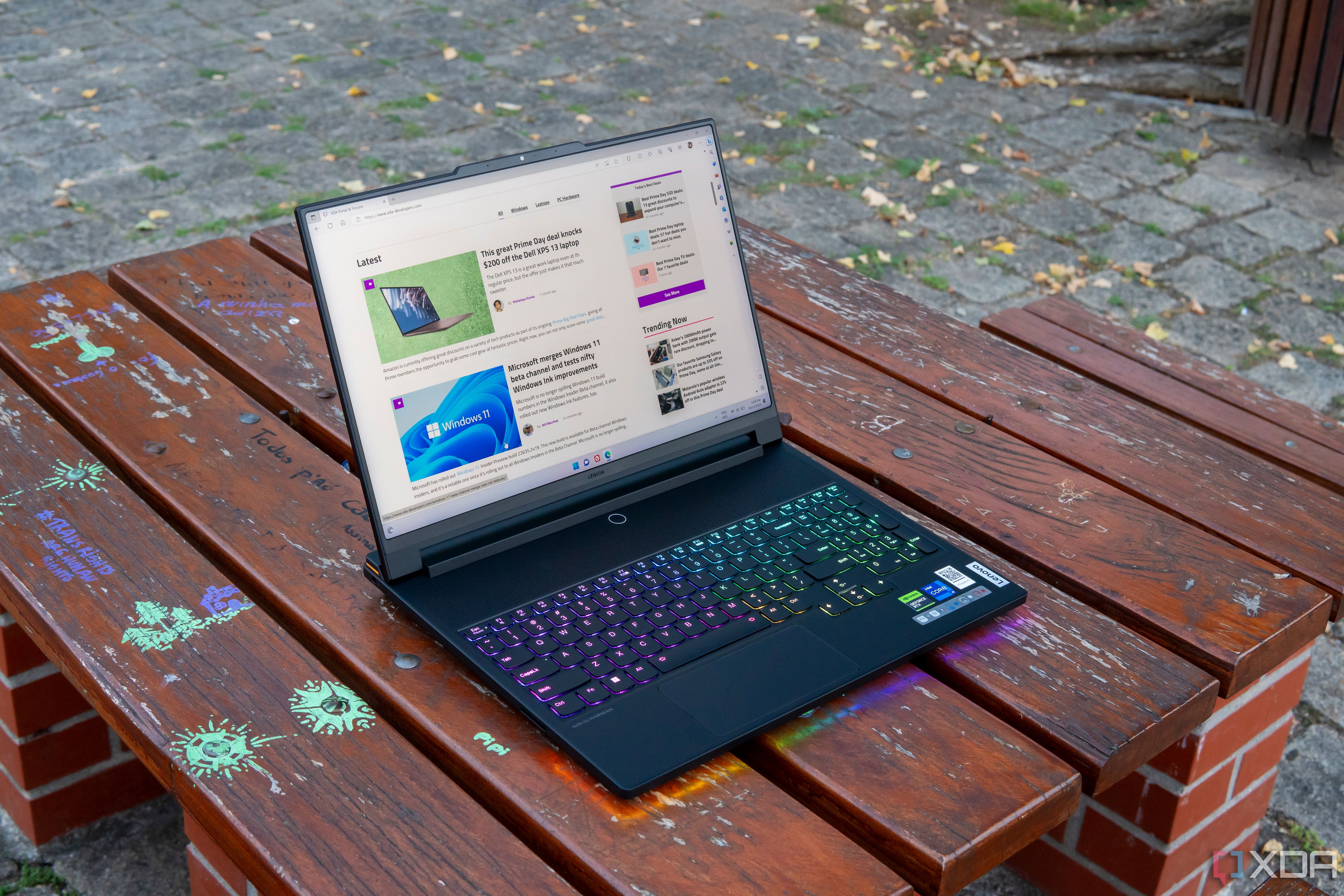 A Lenovo Legion 9i laptop on a wooden table, displaying the XDA homepage 