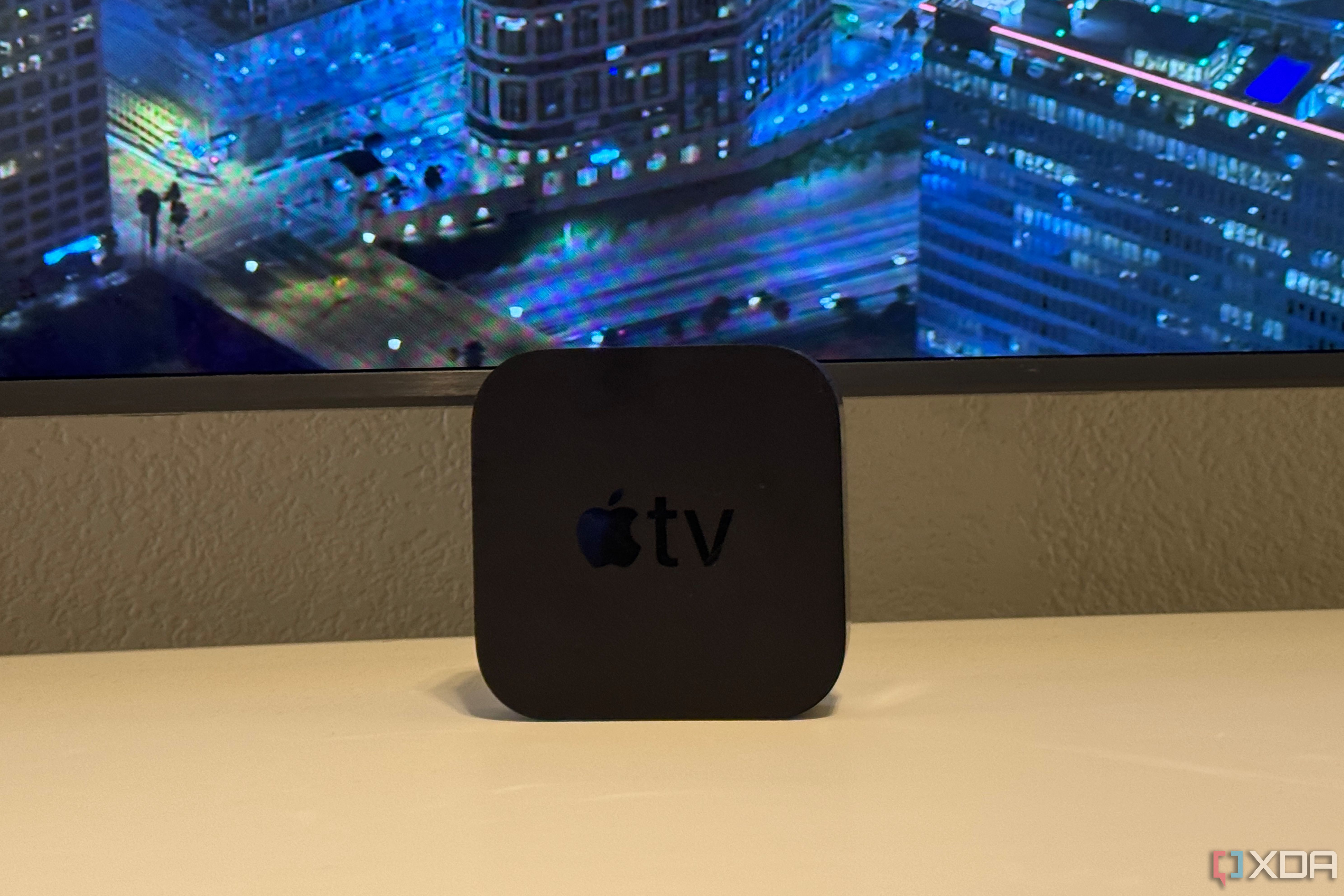 An Apple TV 4K on a desk in front of a TV.