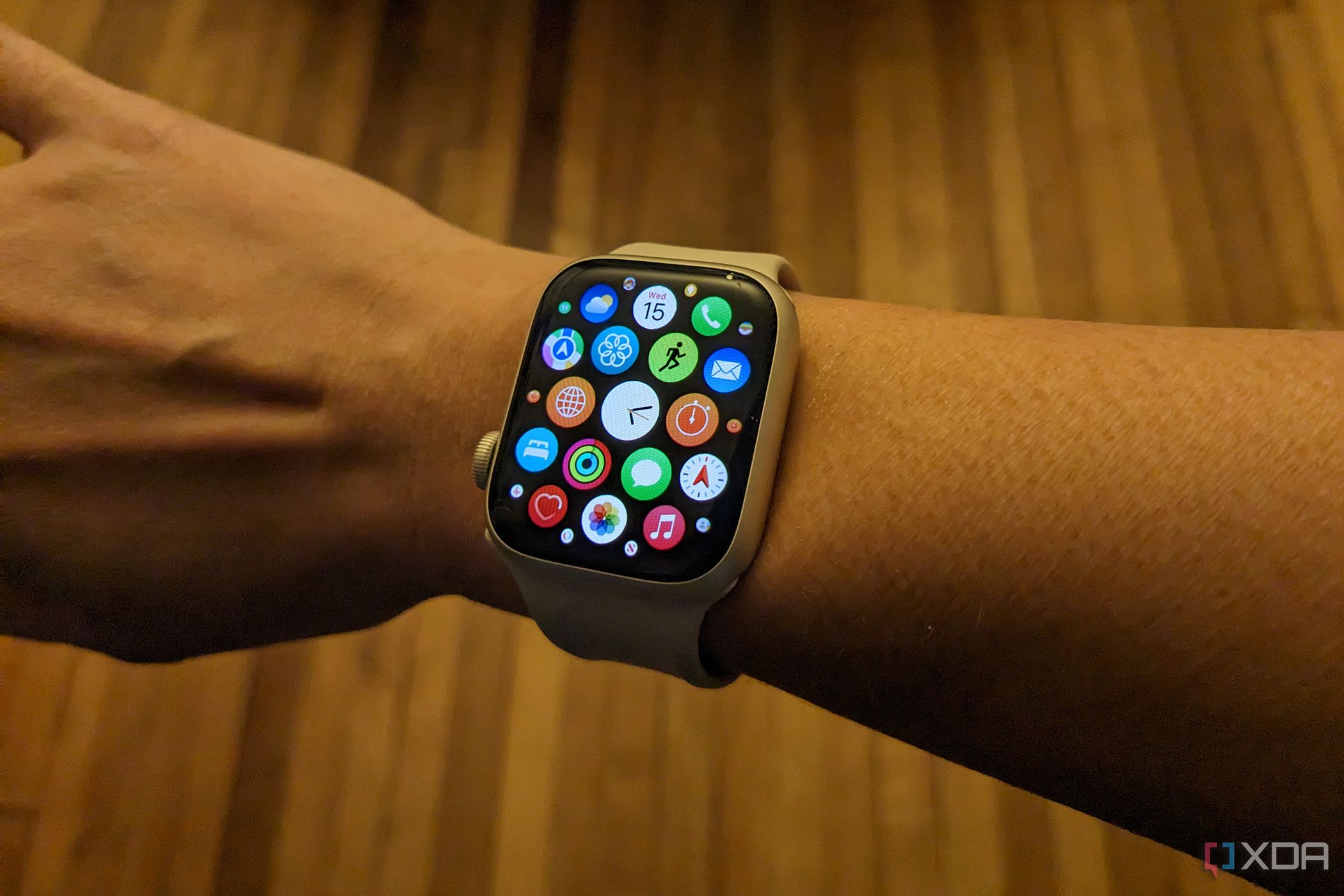 A hand wearing an Apple Watch showing the apps in grid view.