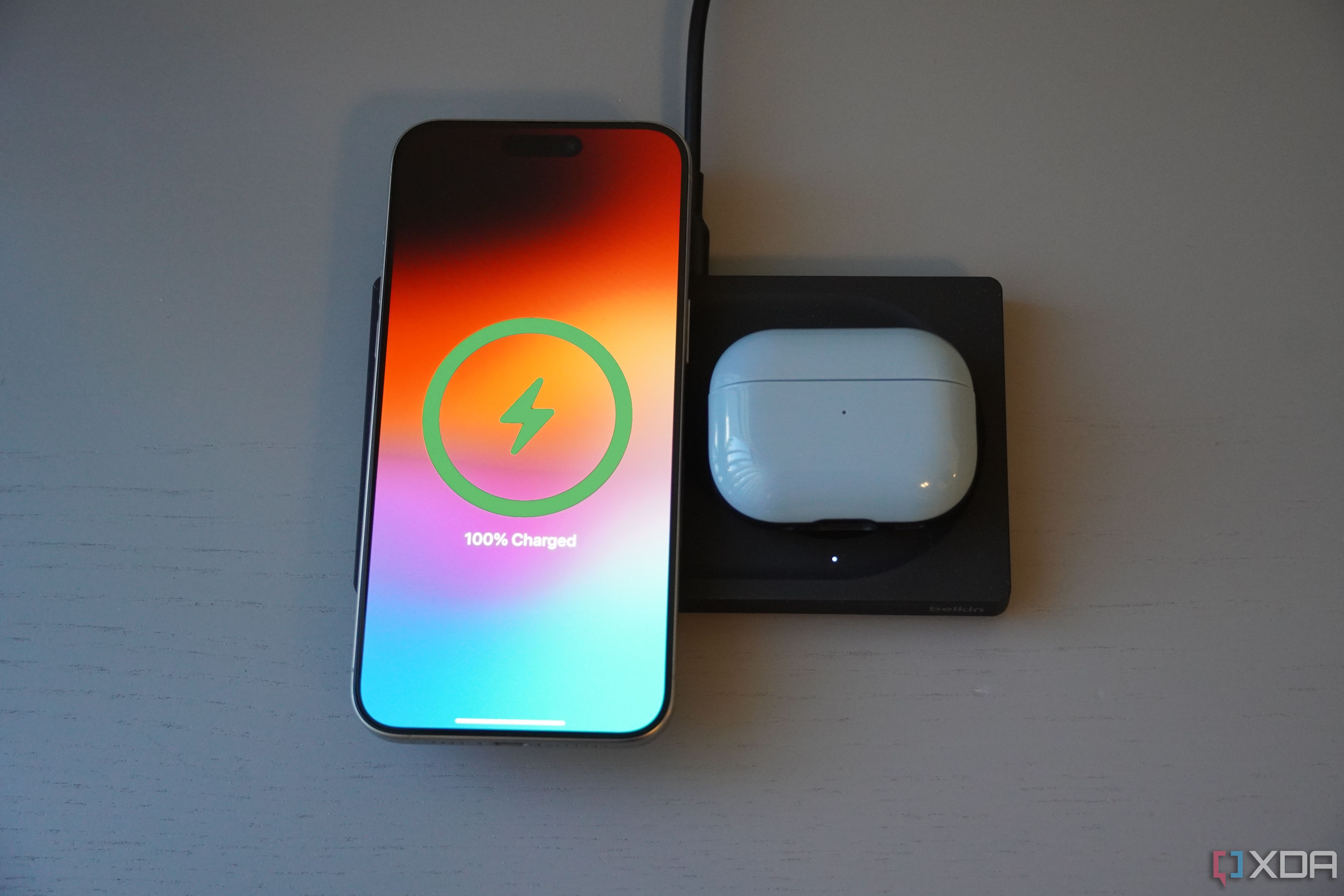 An iPhone and AirPods on the Belkin wireless charging pad. 