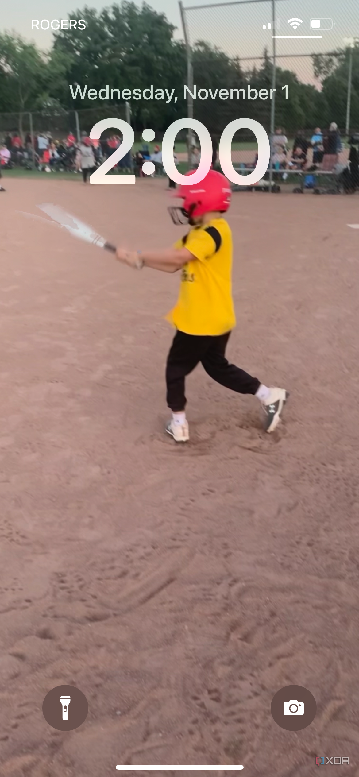 An iPhone lock screen showing a young boy batting a baseball.