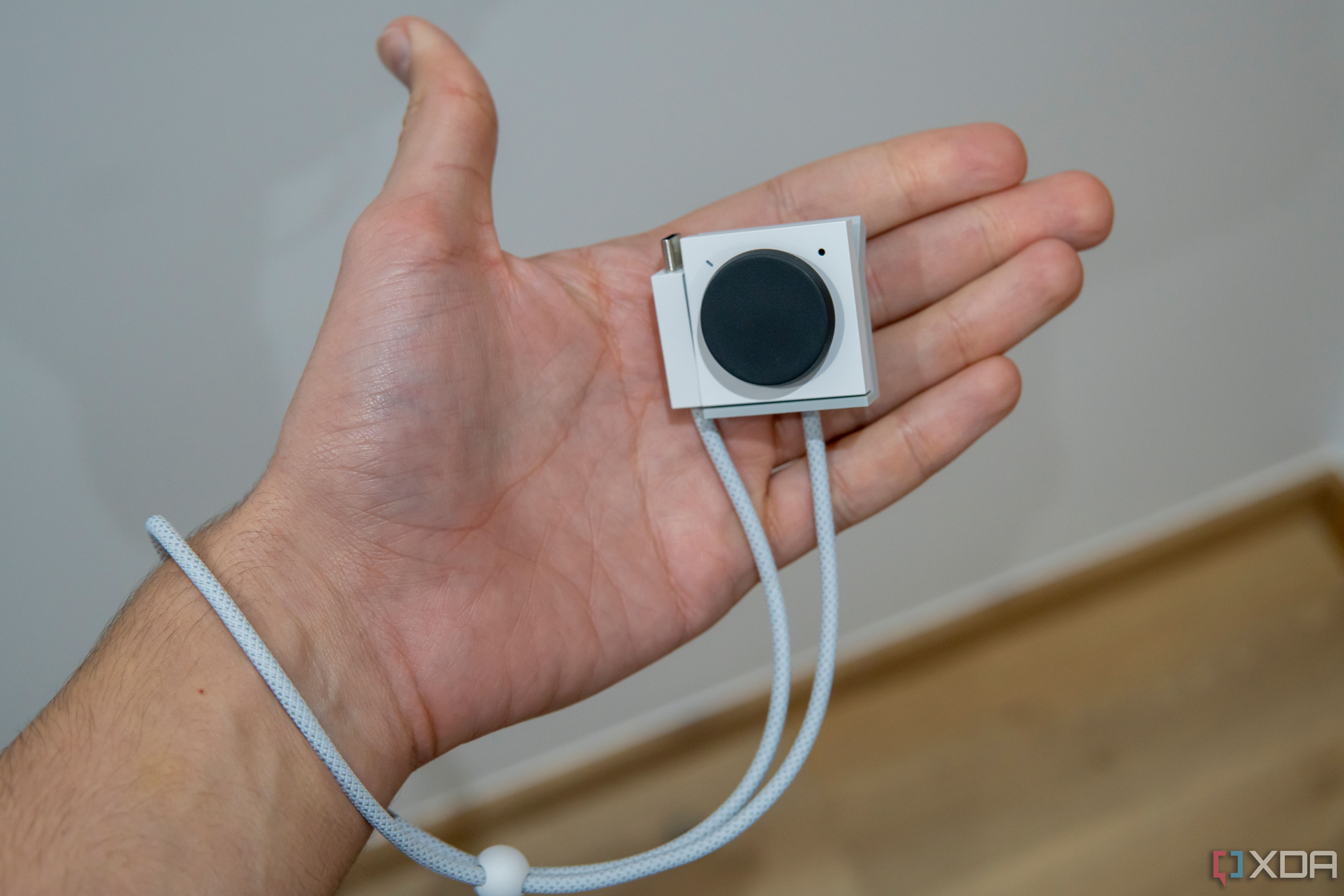 An Opal Tadpole webcam in someone's hand with the USB cable serving as a wrist strap