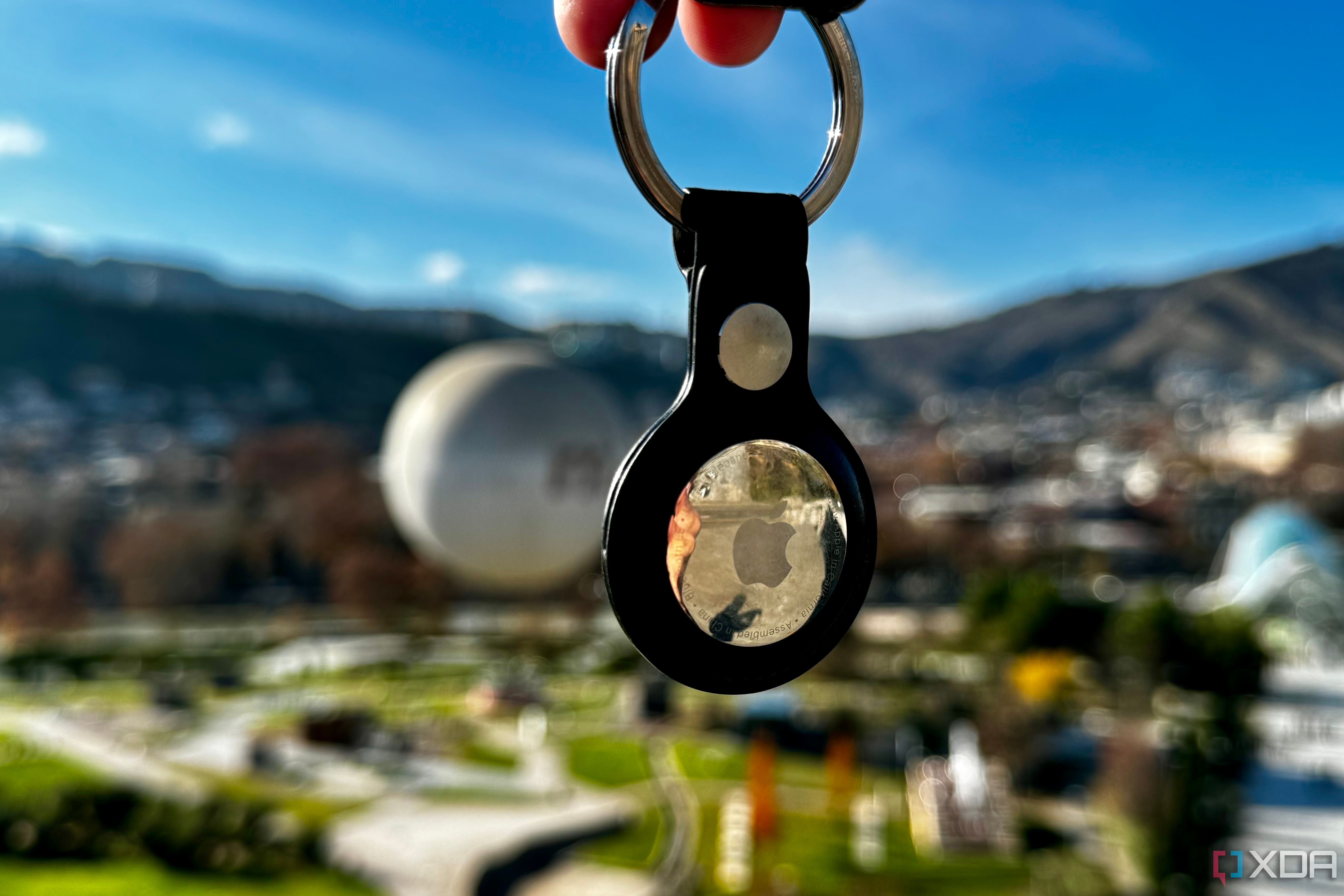 floating Apple AirTag keychain with greenery in the background
