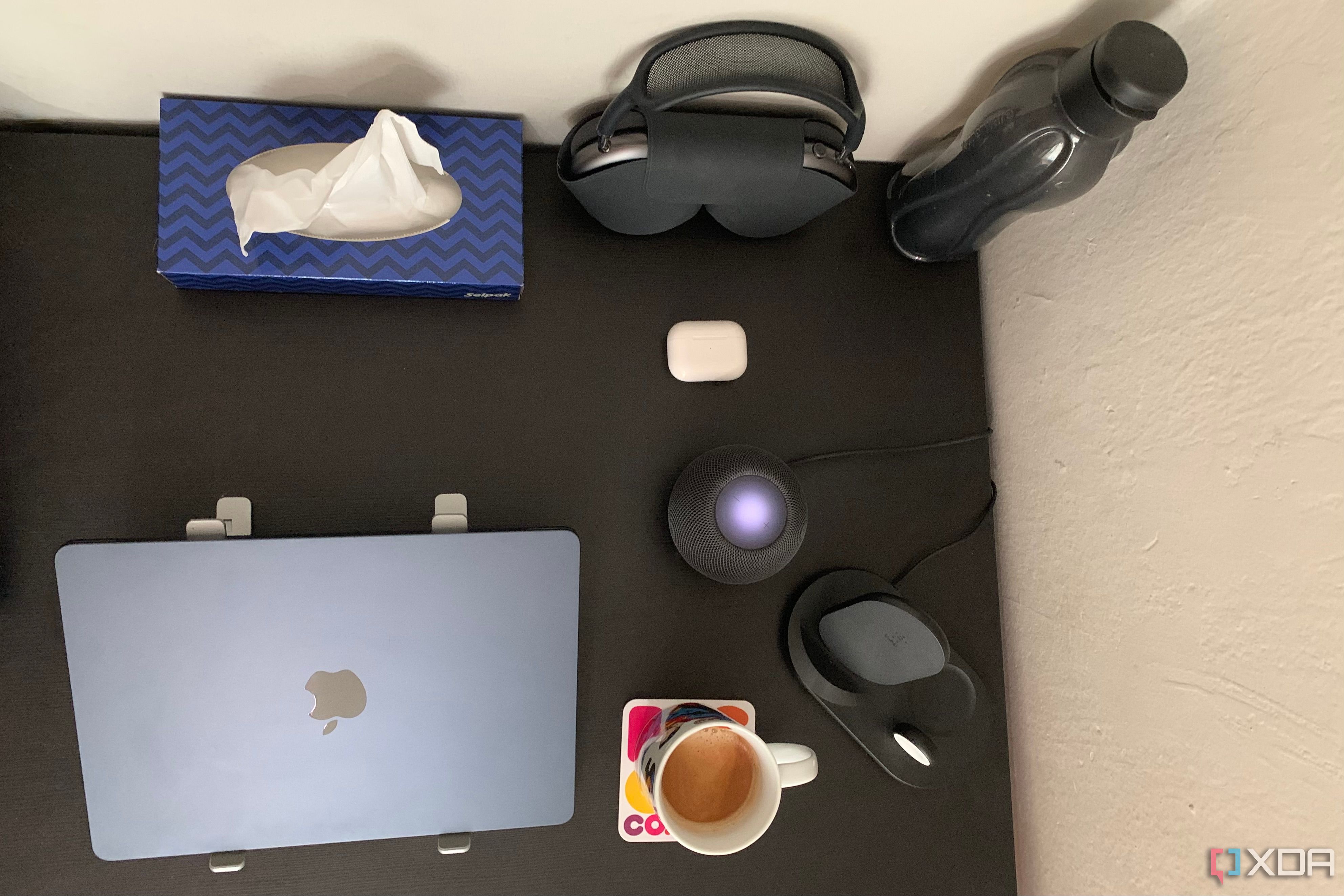 HomePod Mini, MacBook Air M2, AirPods Max, AirPods Pro, and Belkin wireless charger placed on a black table