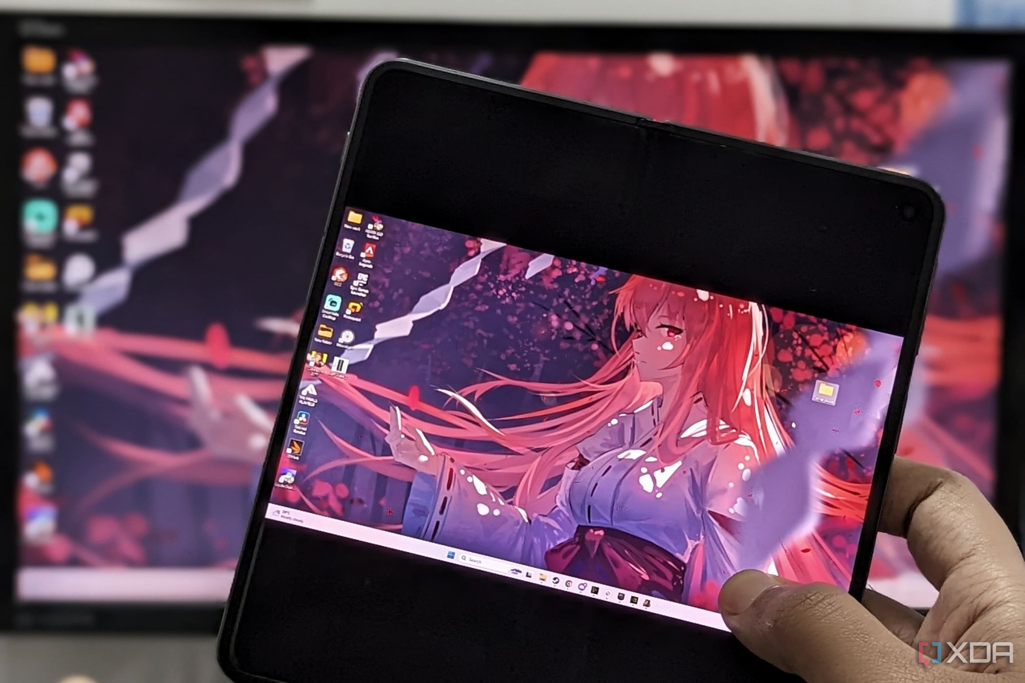 An image showing a person holding a phone displaying the Moonlight app running desktop mirror.