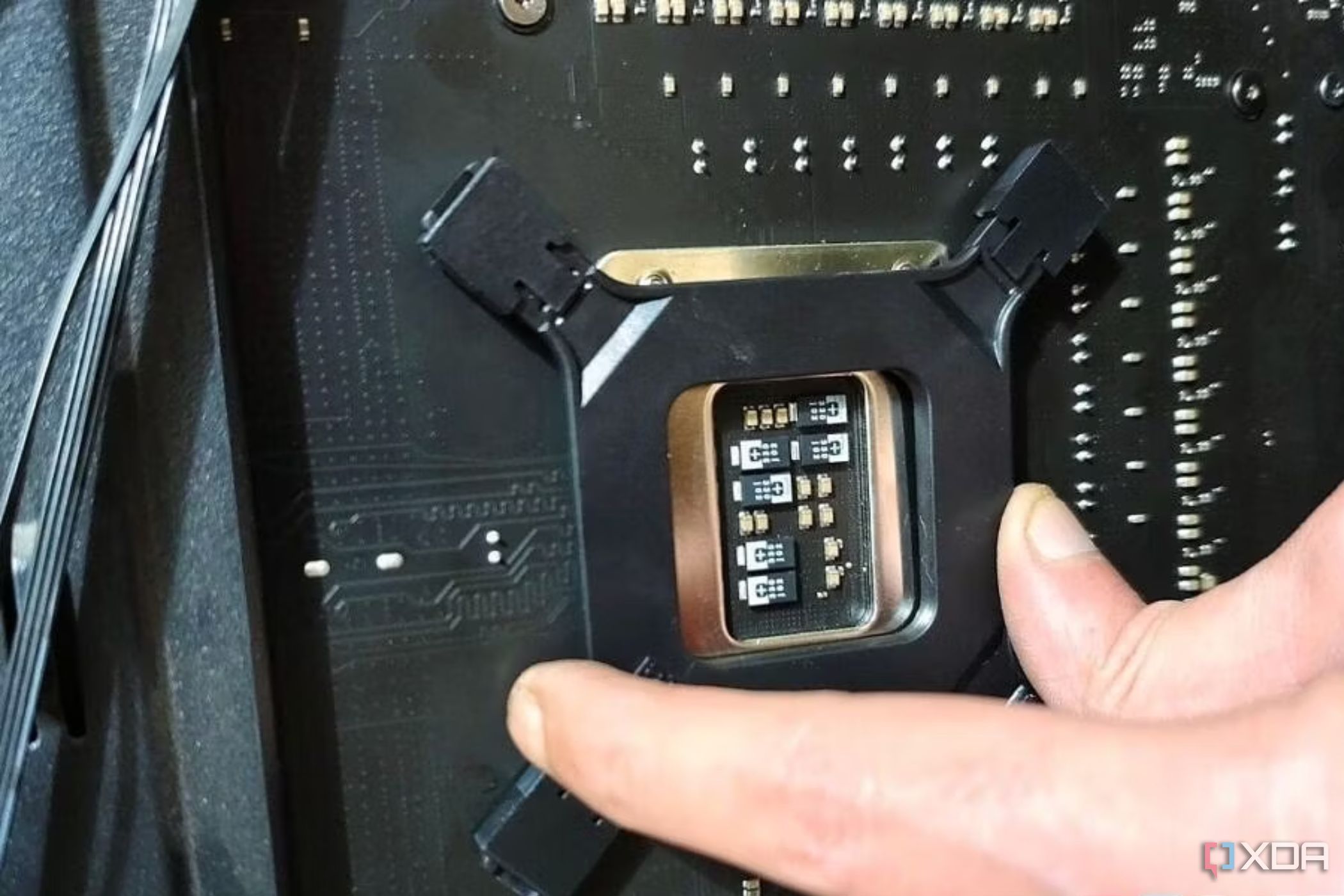 An image showing a person holding the backplate of a CPU cooler on the motherboard for installation.