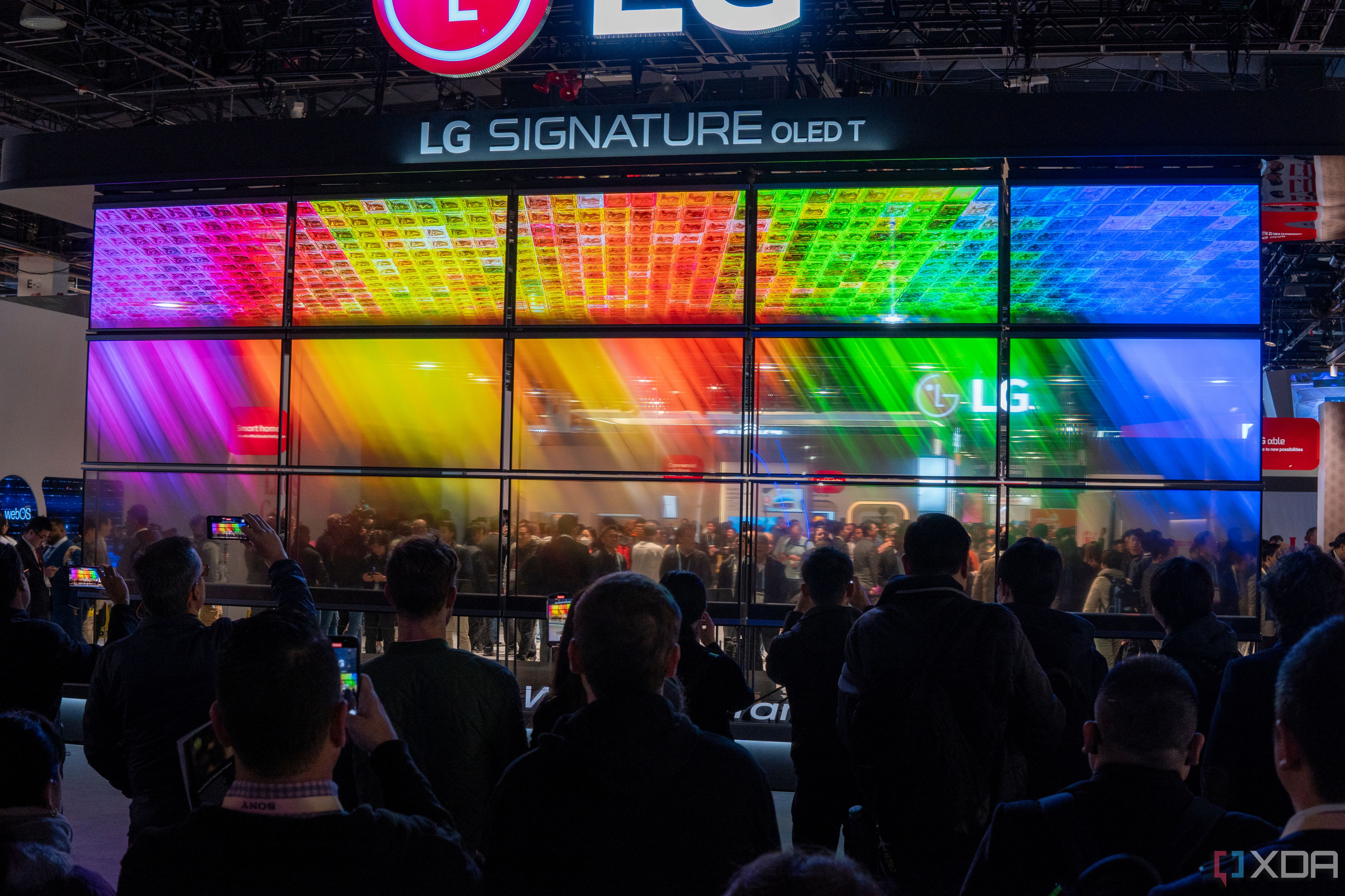 A wall of transparent LG OLED TVs showing a colorful image