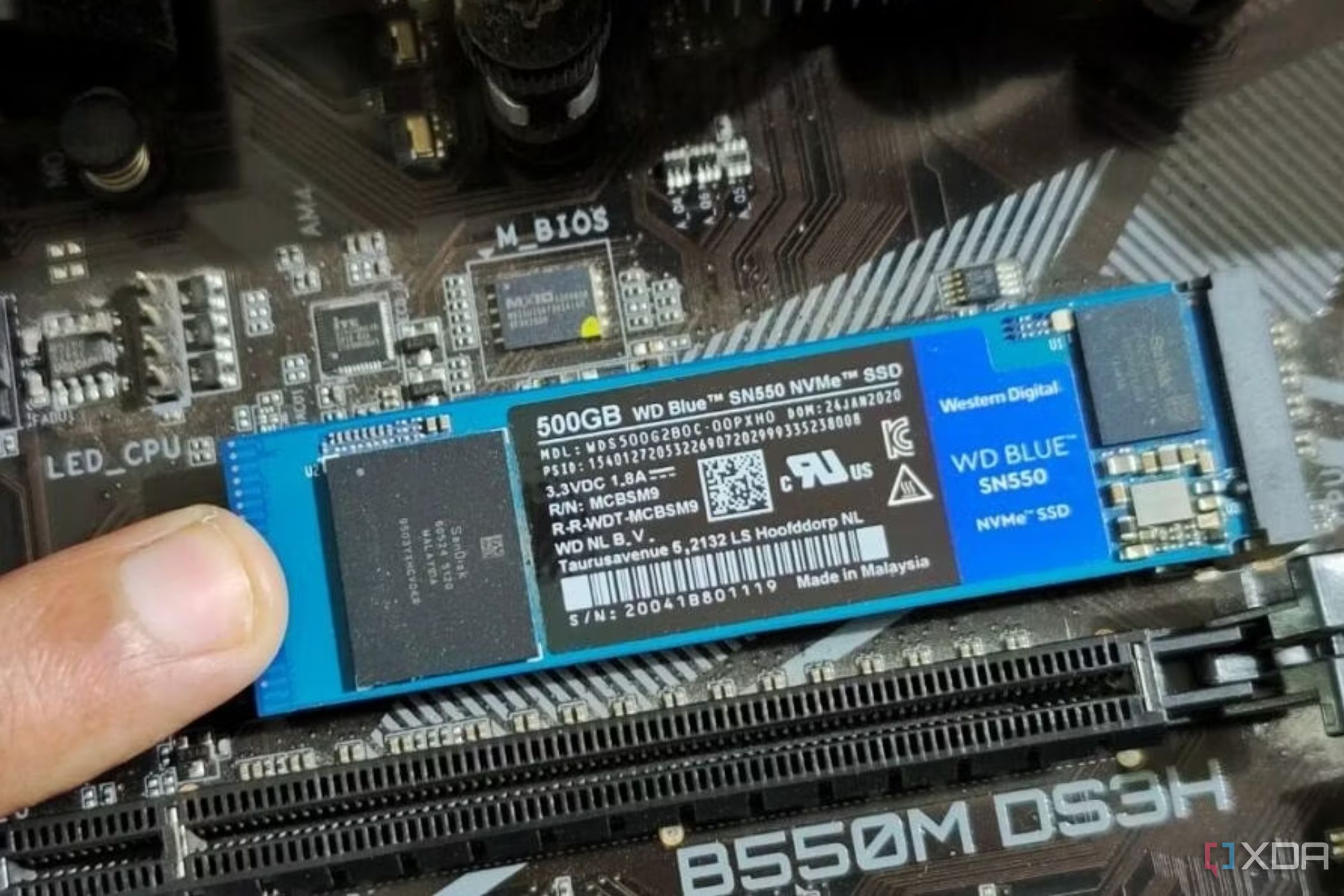 An image showing a person holding an M.2 SSD module in place with their finger.
