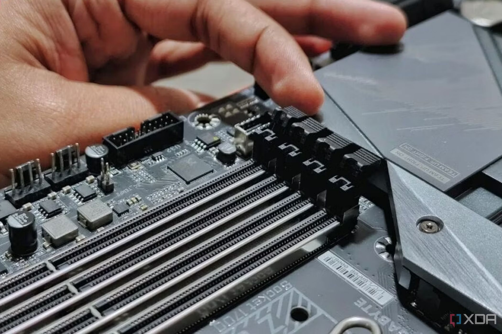 An image showing a person undoing the latches securing the ram modules on the slot.